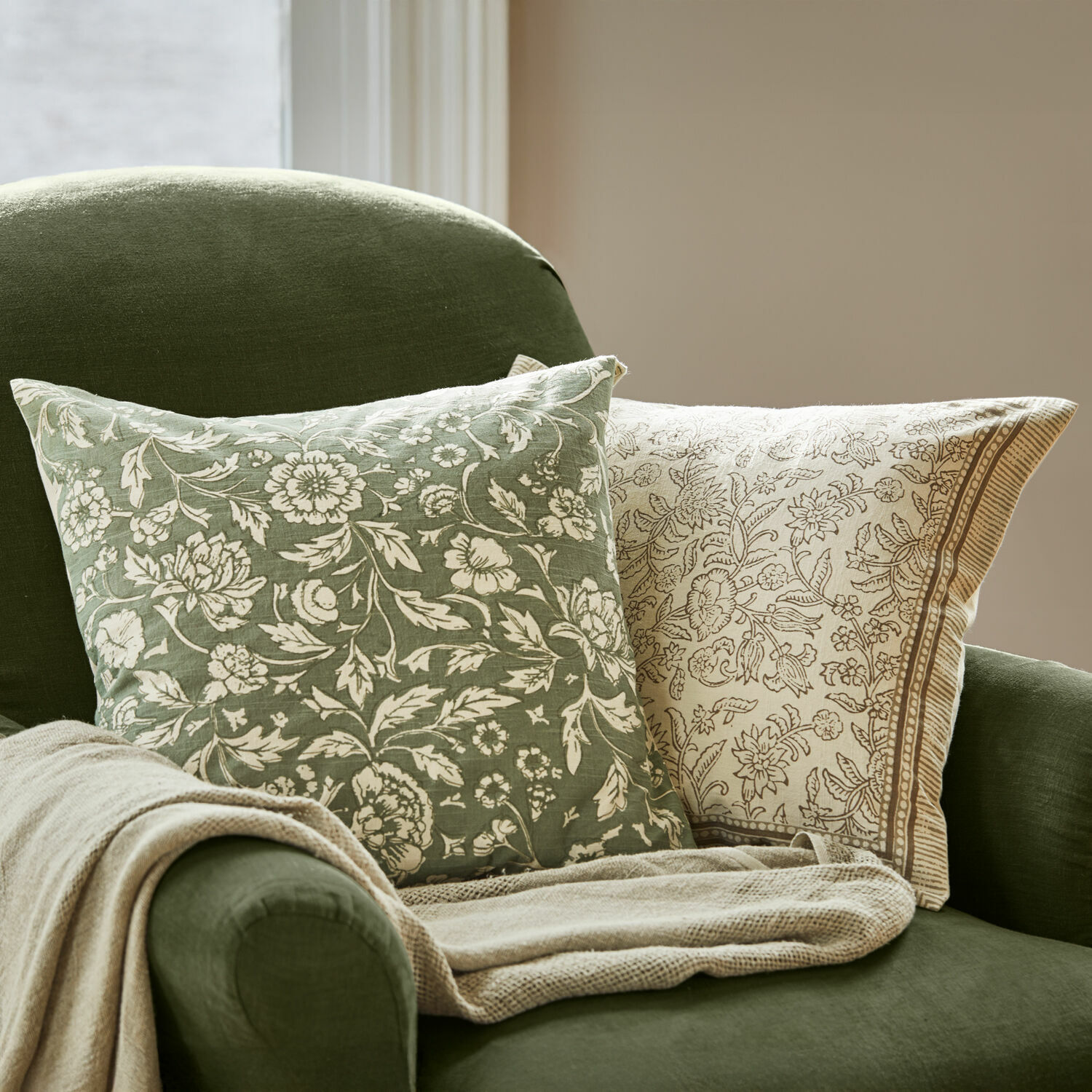 Set de 2 fundas de cojín Ovixal Cojines verde y beige con diseño floral sobre sillón verde con manta beige, decoración de sala
