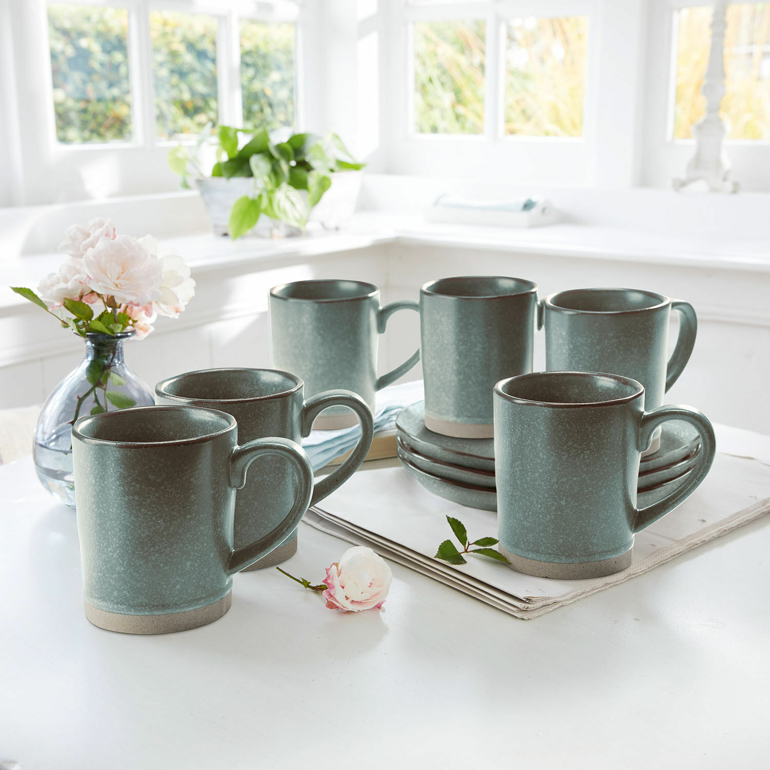 Set de 6 tazas Biarré Conjunto de seis tazas de cerámica verde con platos en mesa clara en interior luminoso