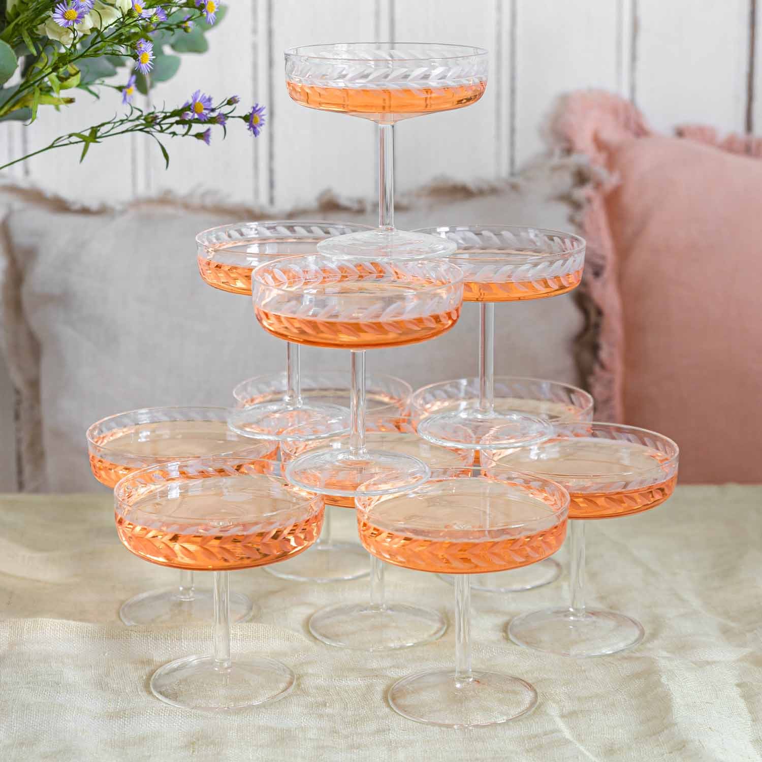 Conjunto de copas de champán de cristal con diseño delicado y bebida rosada sobre mesa