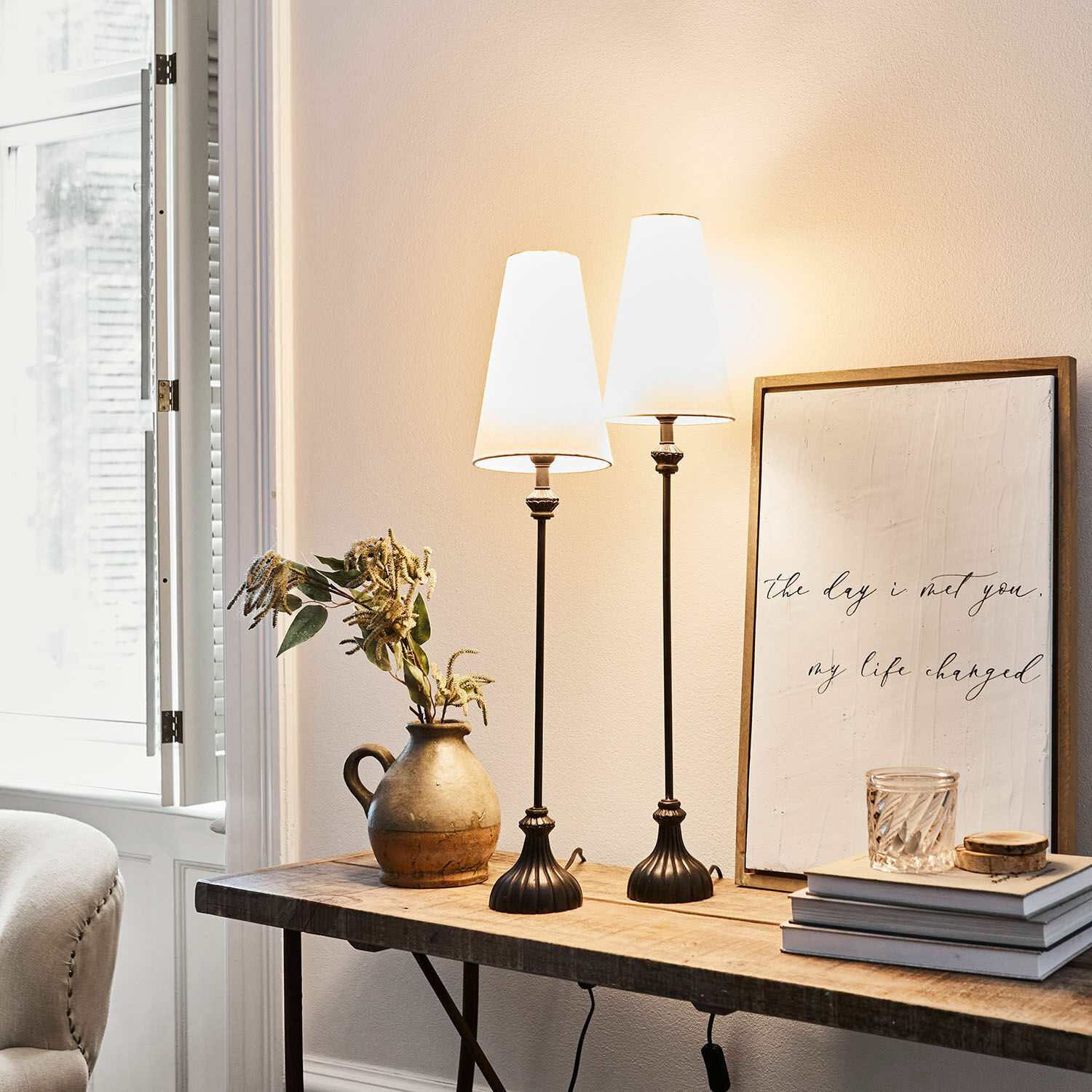 Set de 2 lámparas de mesa Ambrosse Dos lámparas de mesa de metal negro con pantallas blancas sobre mesa de madera en interior luminoso