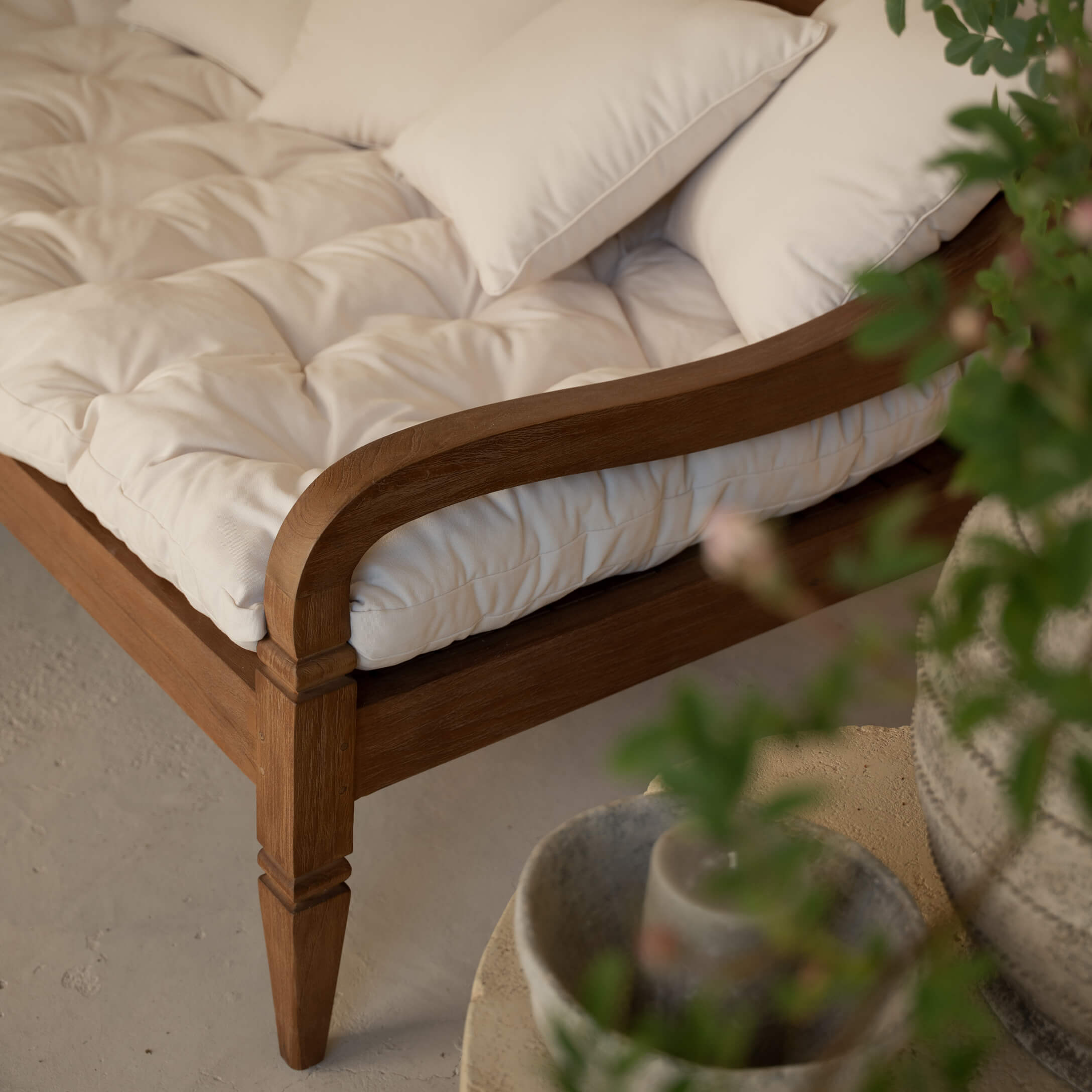 Detalle de sofá de madera con cojín acolchado crema y cojines decorativos suaves
