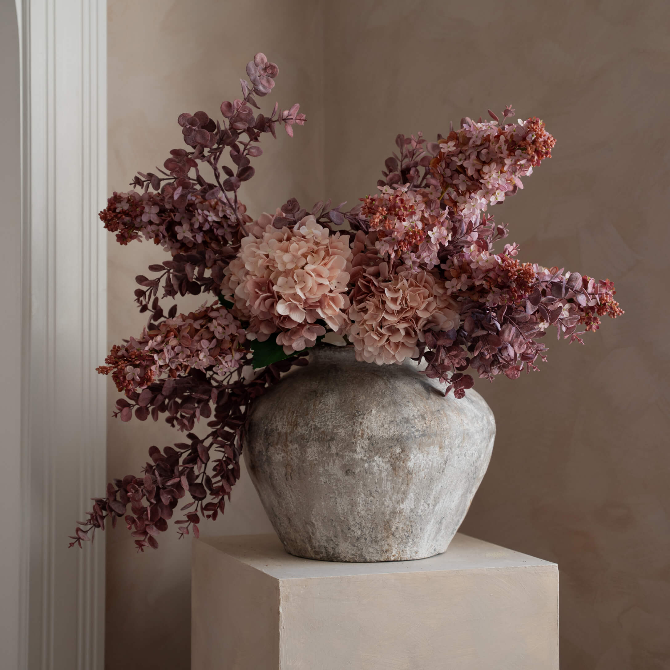 Jarrón decorativo de piedra gris con flores artificiales rosas y violetas para interiores