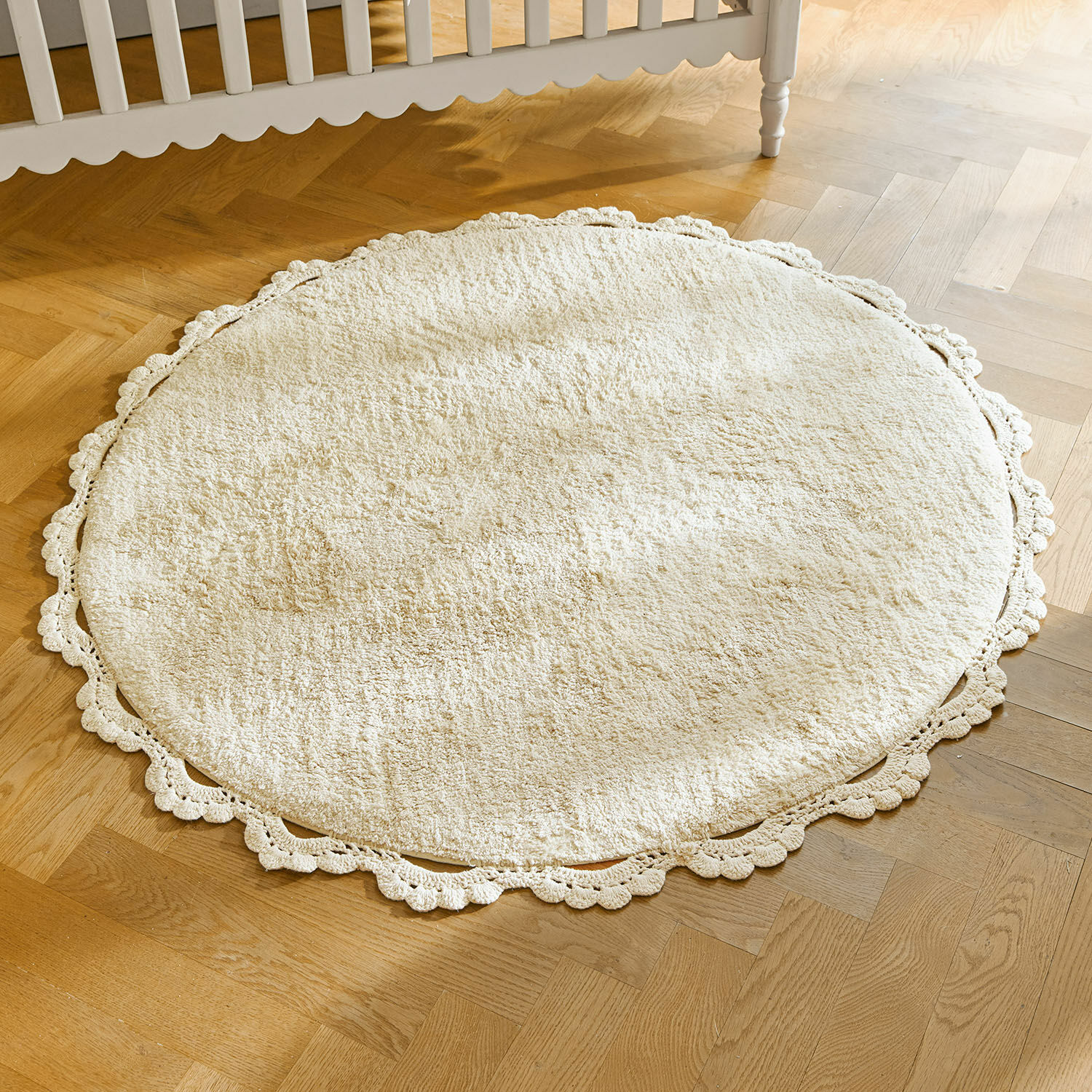 Alfombra Arash Alfombra redonda crema de material suave con borde decorativo de encaje sobre suelo de madera clara