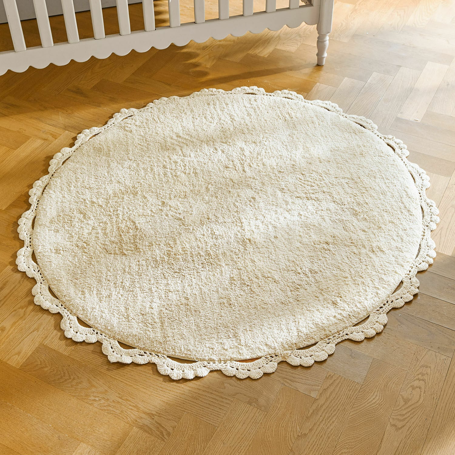Alfombra Arash Alfombra redonda crema de material suave con borde decorativo de encaje sobre suelo de madera clara
