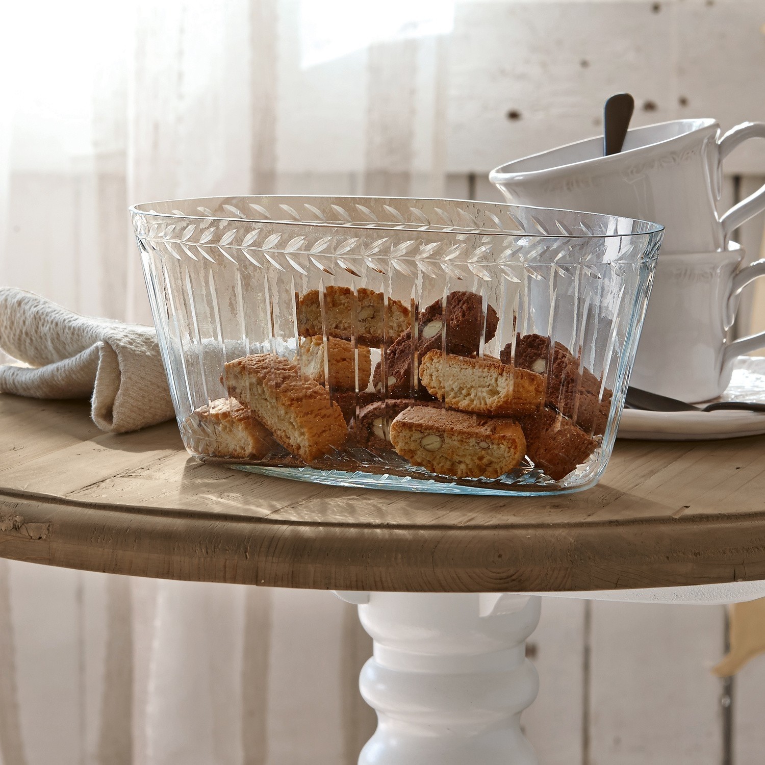 Cuenco de vidrio transparente con diseño decorativo lleno de galletas sobre mesa de madera clara