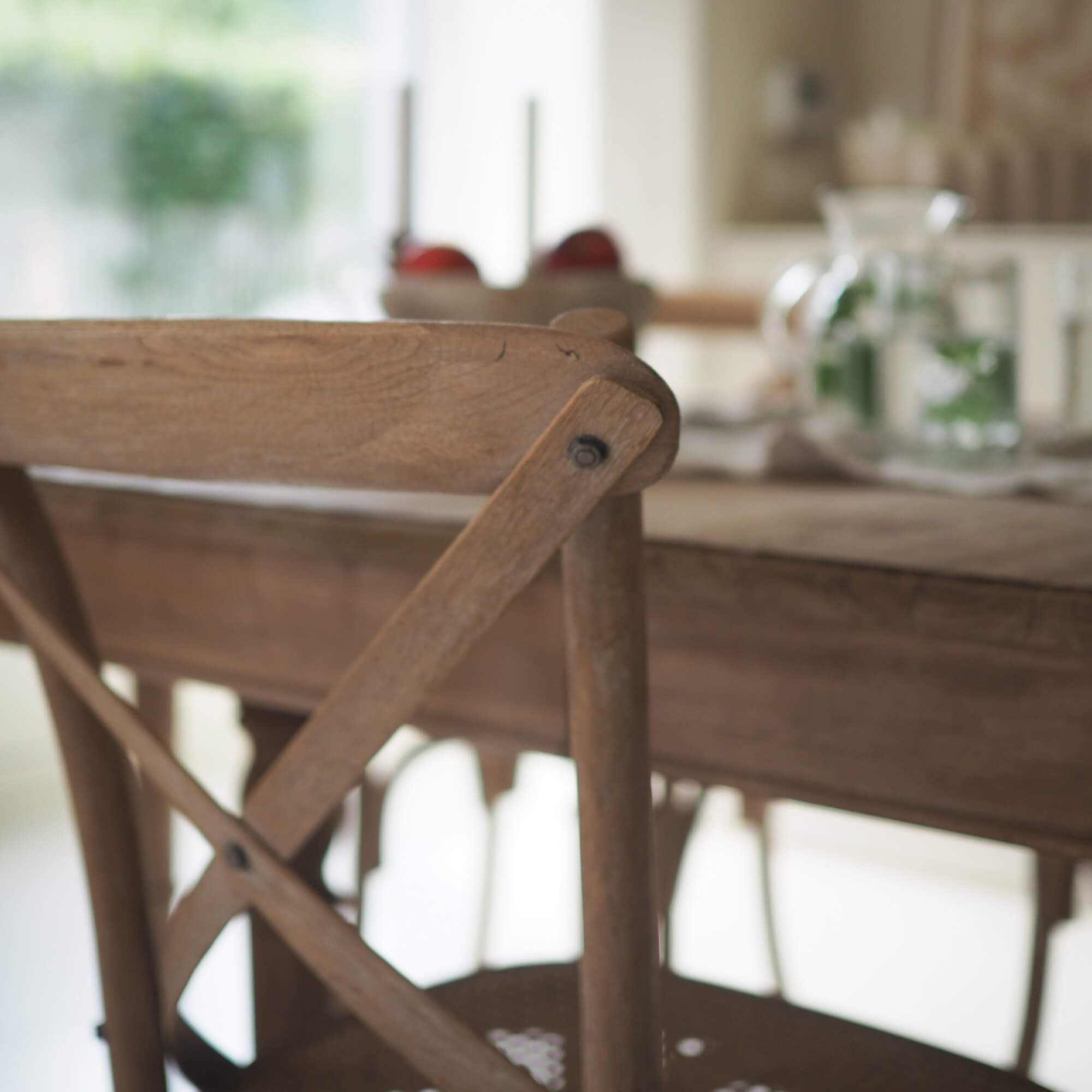 Silla de madera clara con respaldo en forma de X en un comedor acogedor y luminoso