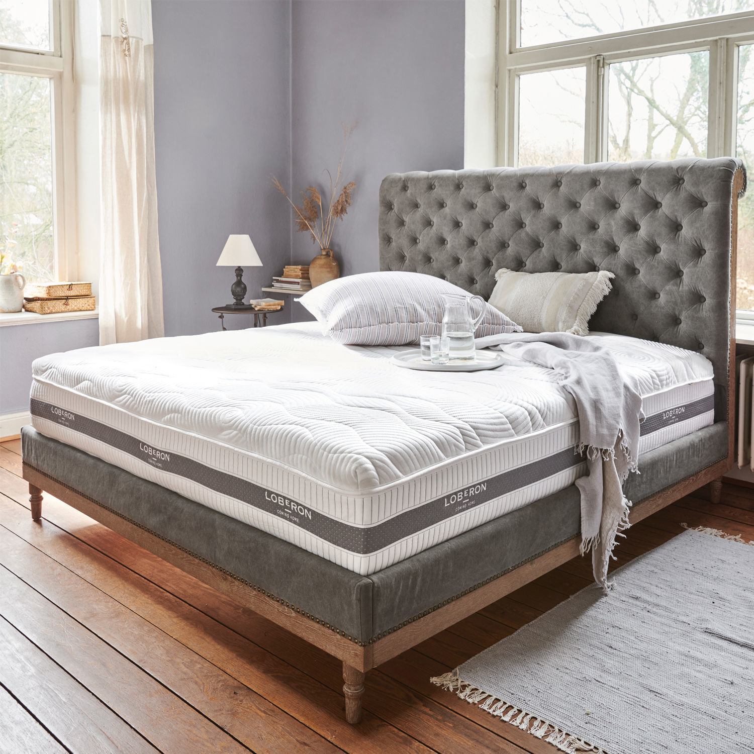 Colchón con topper 180x200 Raillimont Cama tapizada gris con cabecero capitoné y colchón blanco Loberon en dormitorio luminoso