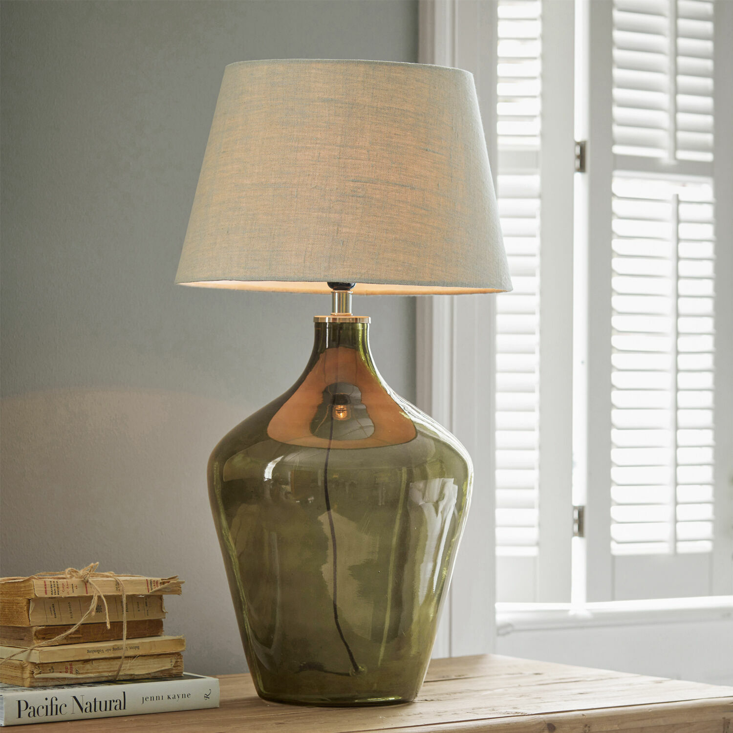 Lámpara de mesa Morazan Lámpara de mesa de vidrio verde con pantalla beige sobre mesa de madera con libros