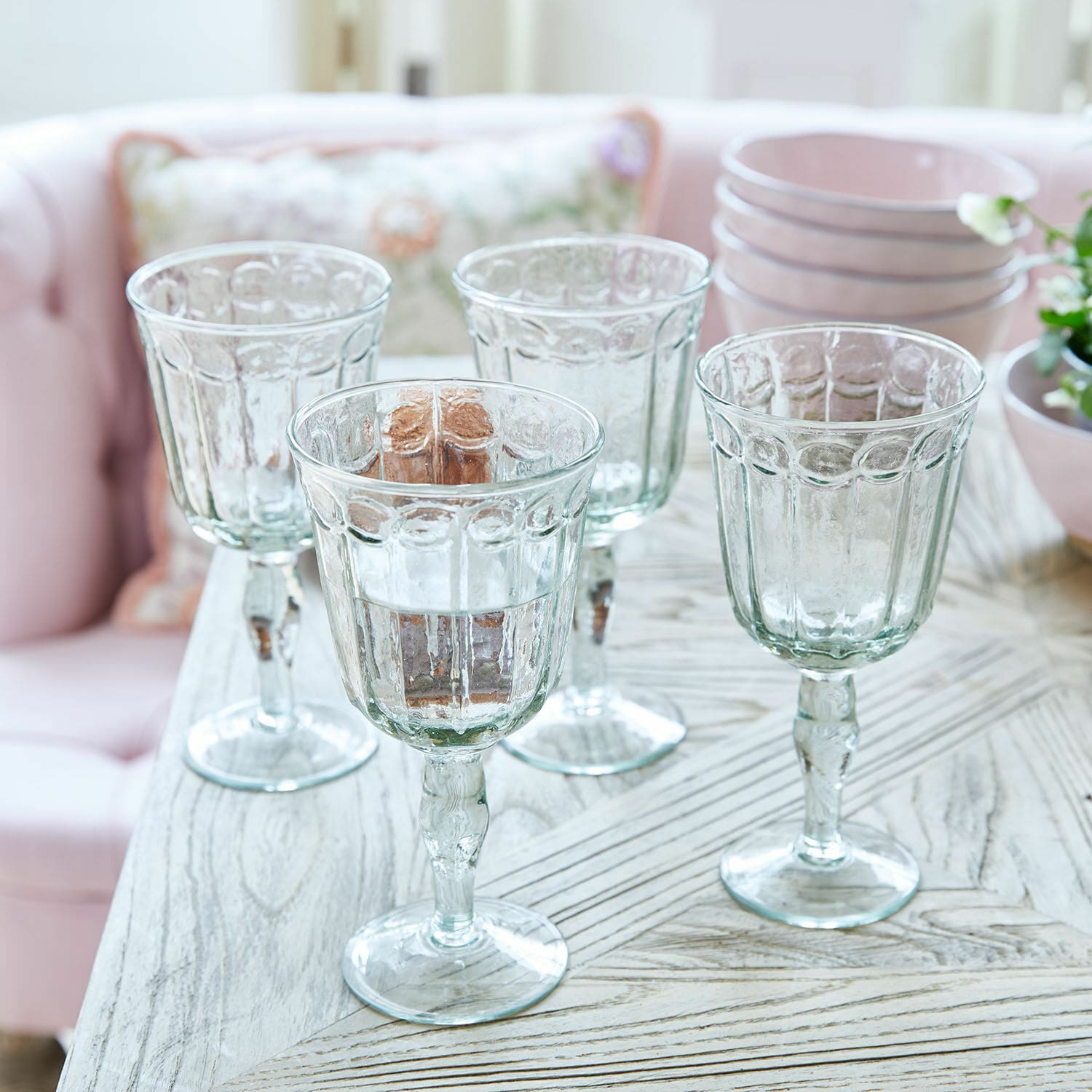 Set de 4 vasos Jolielle Conjunto de cuatro copas transparentes con diseño decorativo sobre mesa de madera clara
