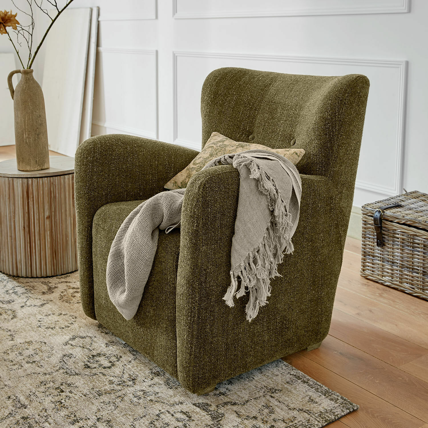 Sillón verde tapizado en tela suave estilo vintage con manta decorativa en sala de estar