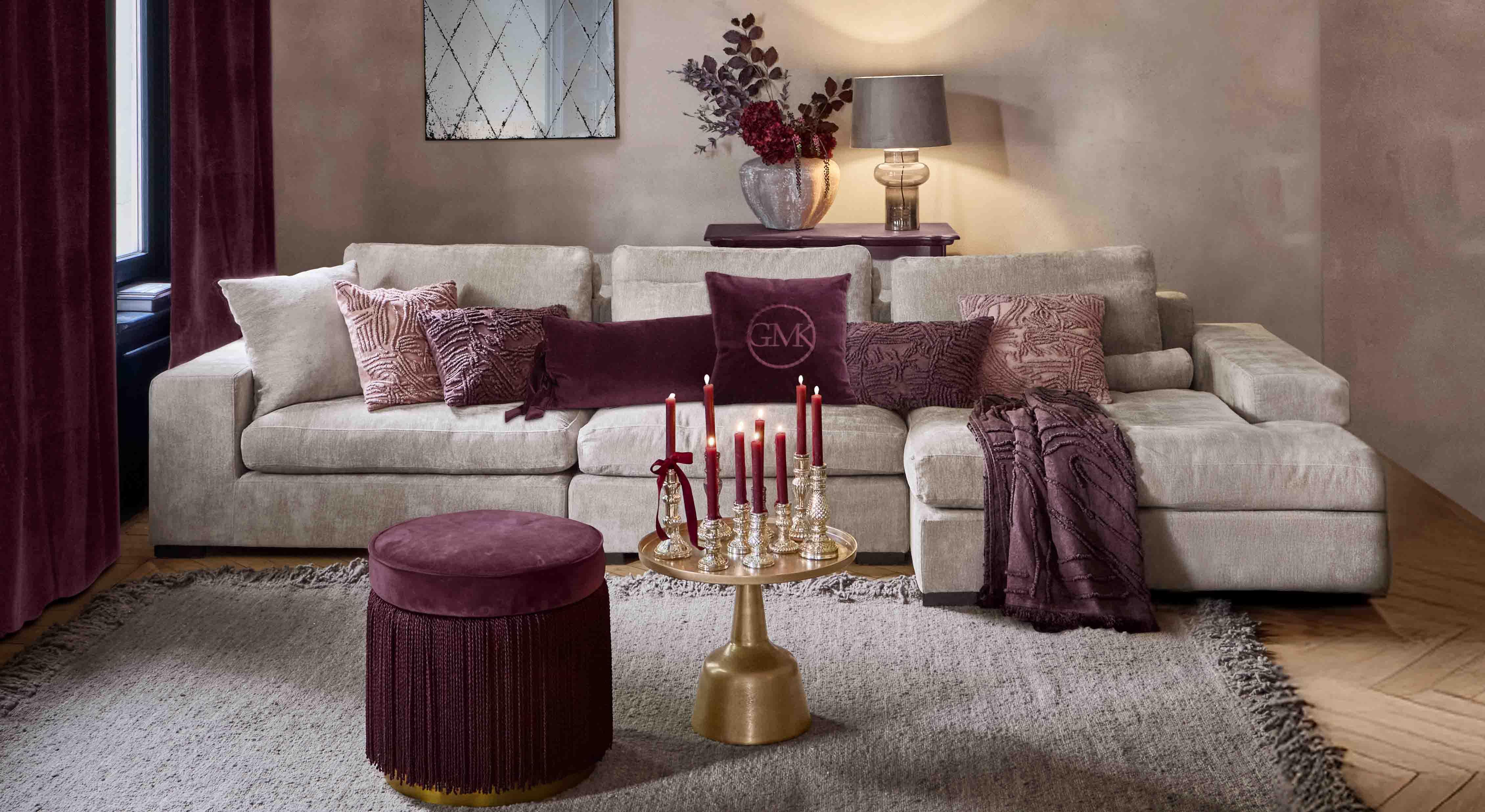 Sofá beige con cojines suaves y detalles burdeos en salón elegante con lámpara y espejo