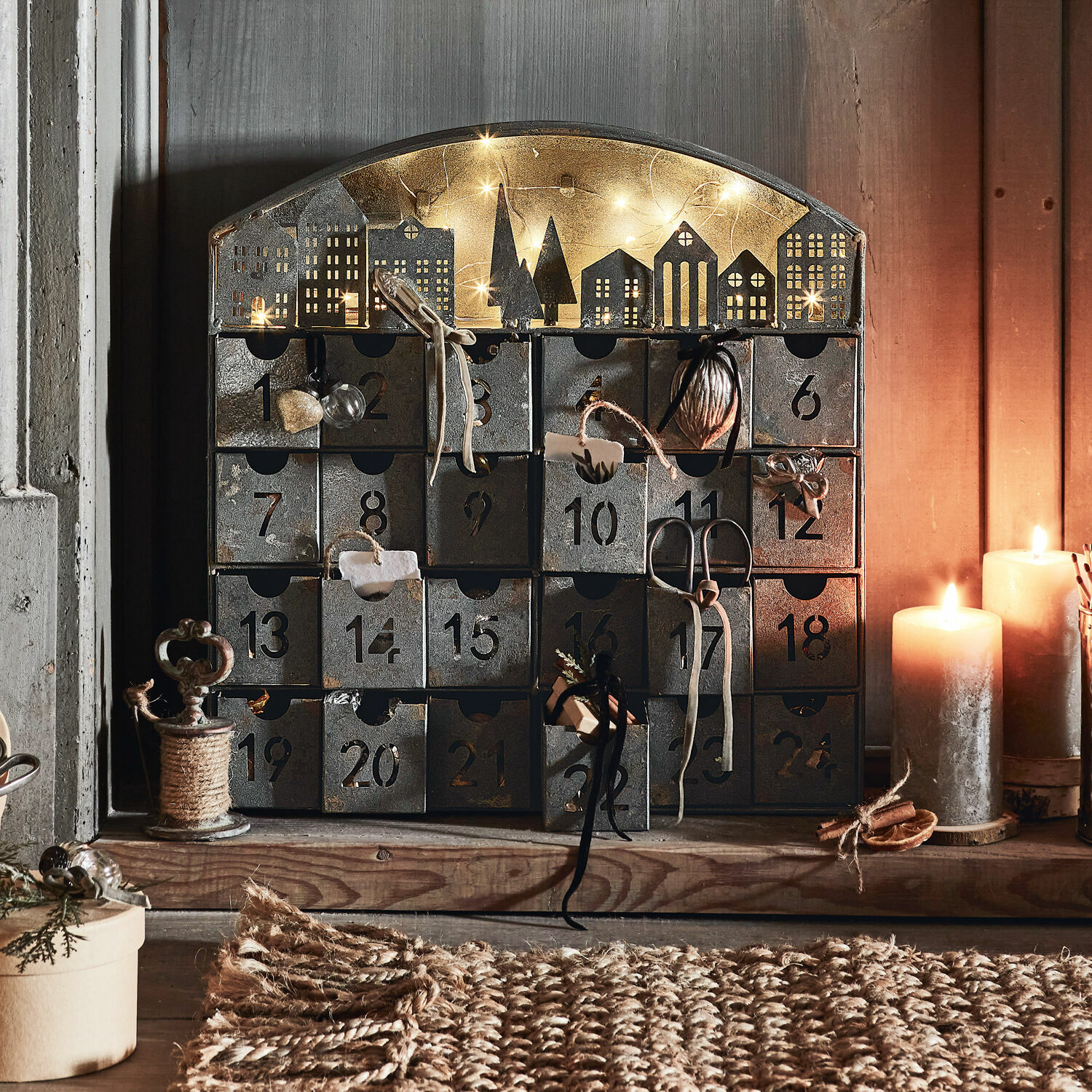 Calendario de Adviento Léran Calendario de adviento metálico con 24 cajones numerados y decoración de casas iluminada con velas
