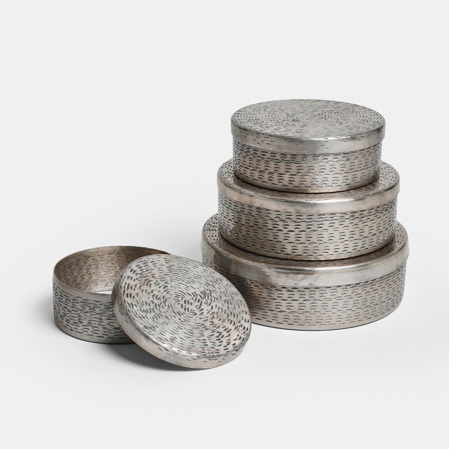 Conjunto de tres cajas redondas de metal plateado con tapas texturizadas para almacenamiento