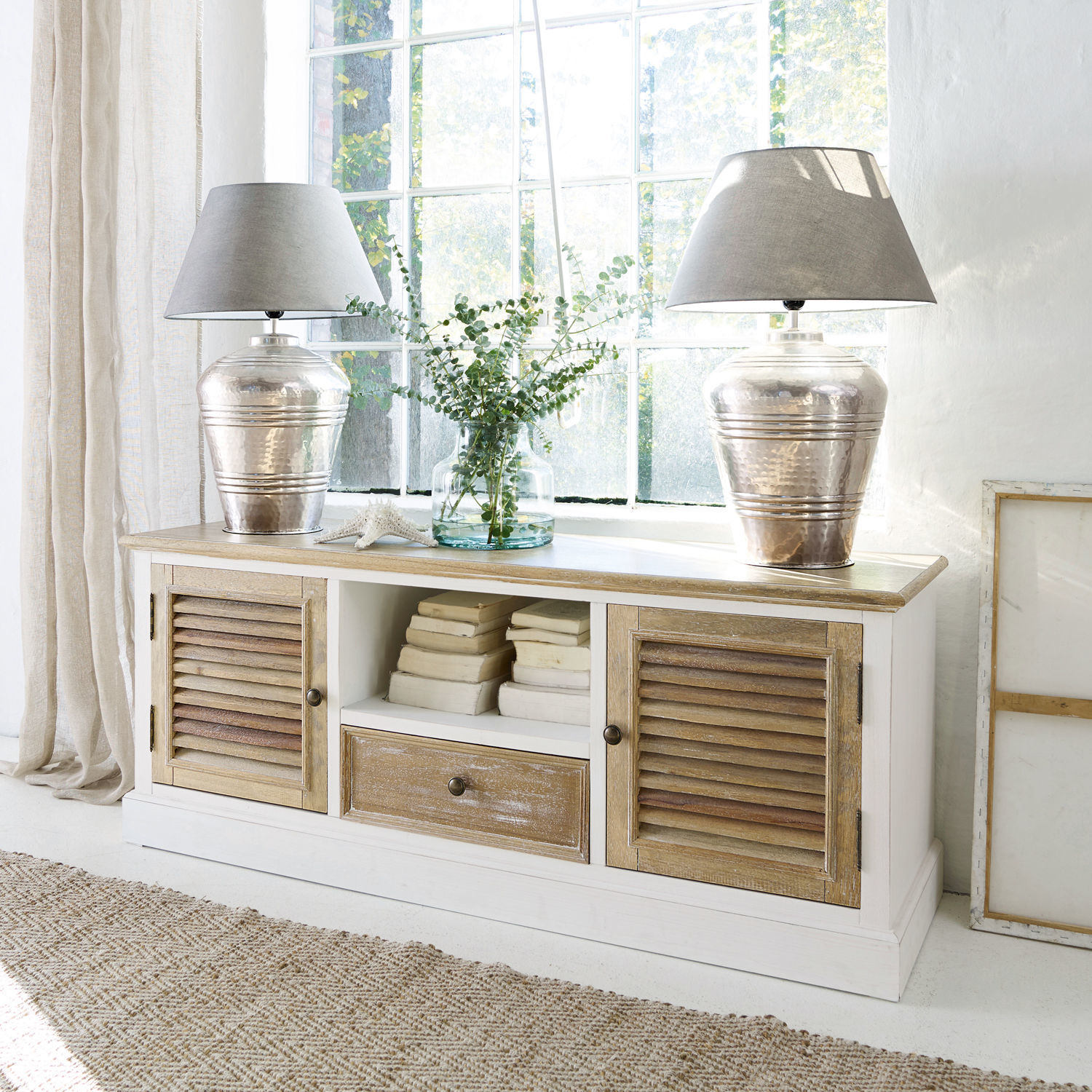 Aparador Glencoe Aparador de madera blanca con tapa natural y puertas de persiana, decorado con lámparas y libros
