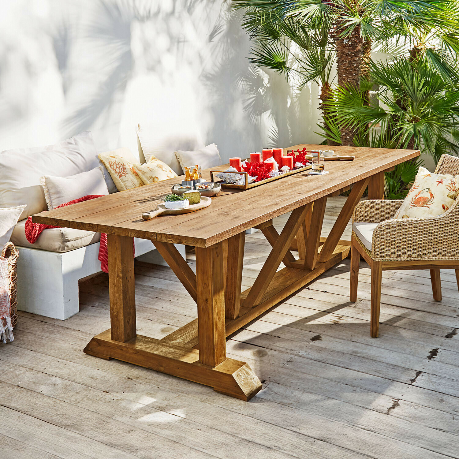 Mesa Melvoro Mesa de comedor grande de madera de teca natural en terraza con velas rojas y aperitivos decorativos