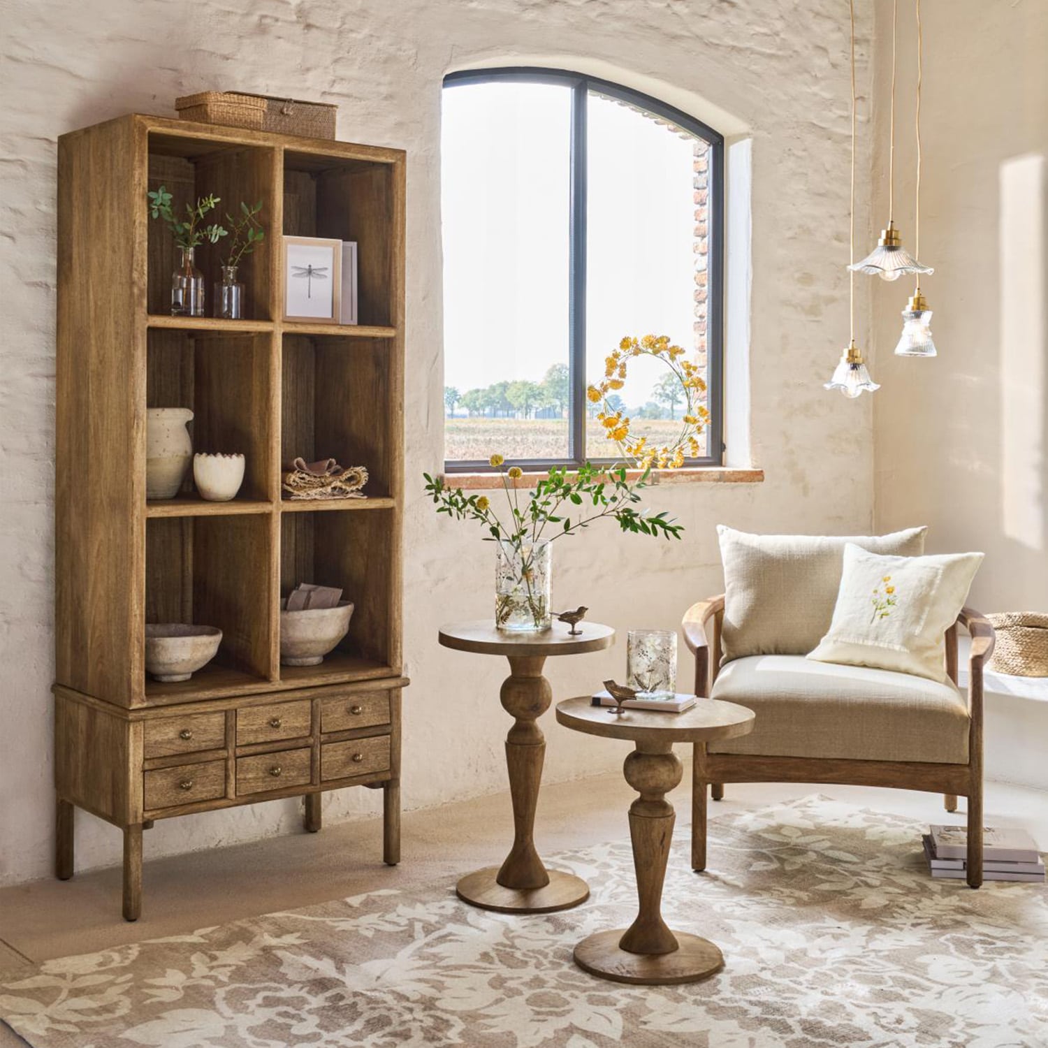 Mueble de madera con cajones y mesas auxiliares en tono natural en salón luminoso con sillón beige