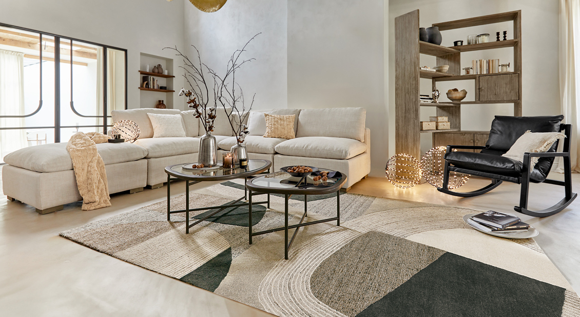 Salón moderno con sofá beige, sillón mecedor negro y alfombra geométrica, iluminación decorativa