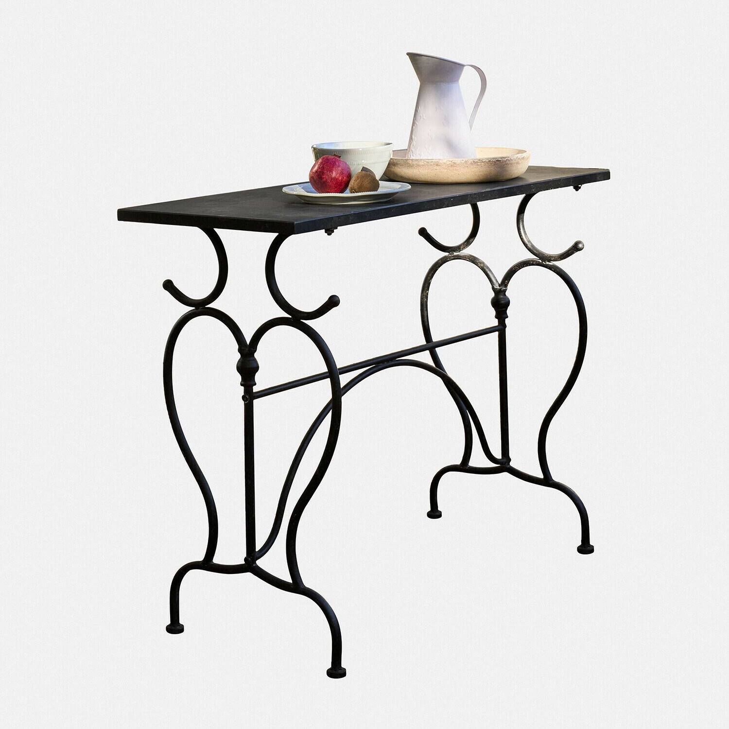 Mesa Cauvrel Mesa de metal negro con patas decorativas y superficie, con vajilla y frutas encima