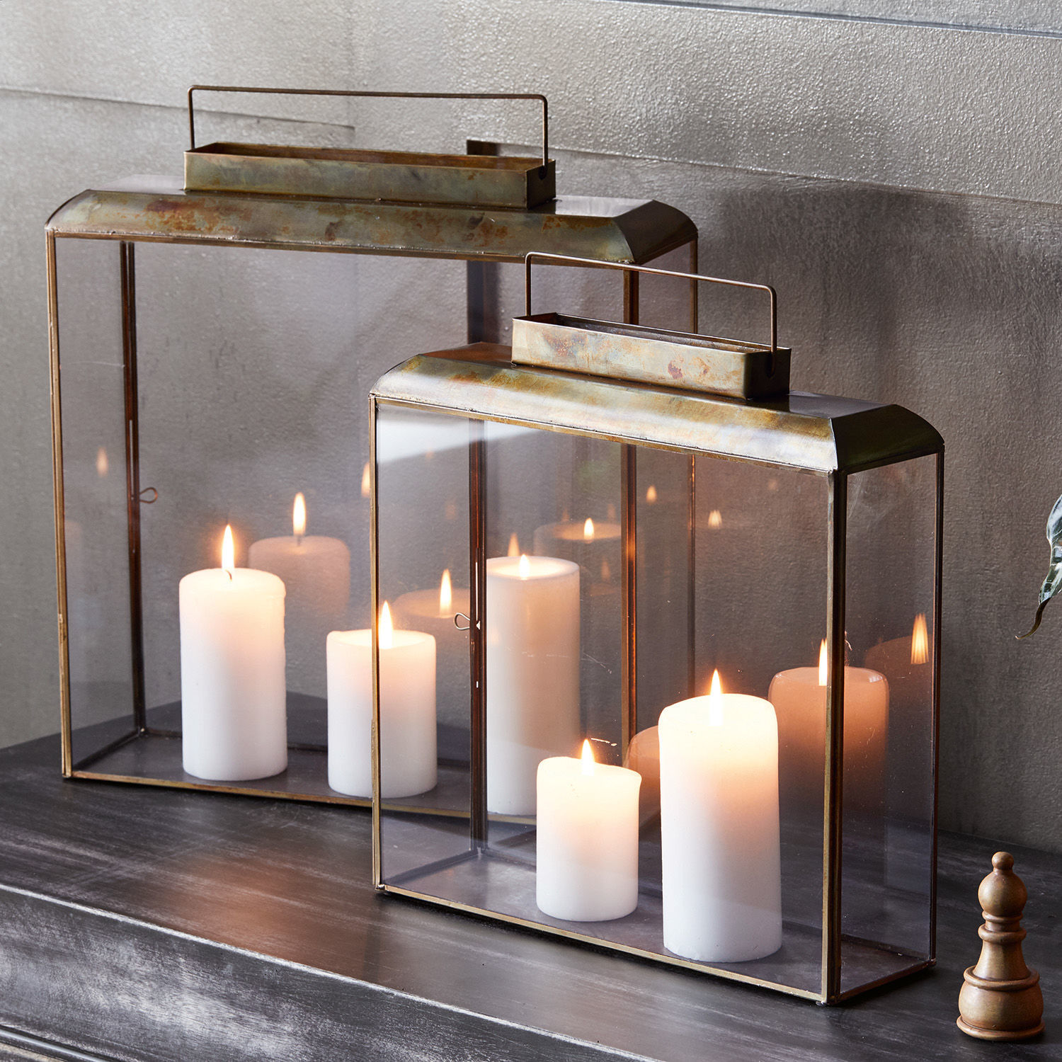 Set de 2 faroles Estrelle Dos faroles metálicos con vidrio transparente y velas blancas sobre superficie oscura