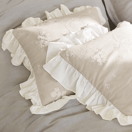 Cojín Clarissa beige con bordado y volante blanco sobre fondo gris, cojín decorativo elegante