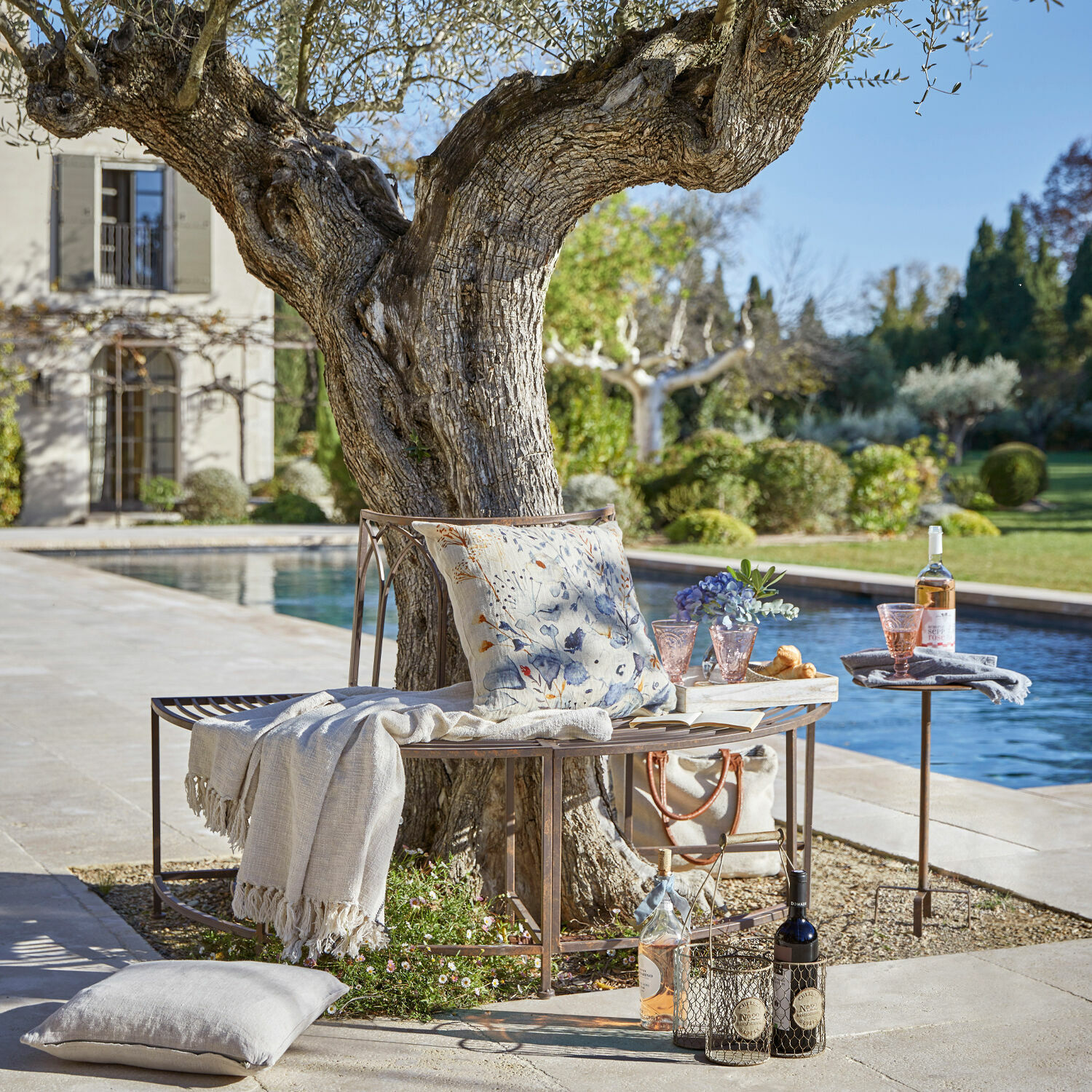 Banco Sherburne Banco metálico alrededor de un árbol con cojín y manta junto a piscina en jardín para relajarse al aire libre