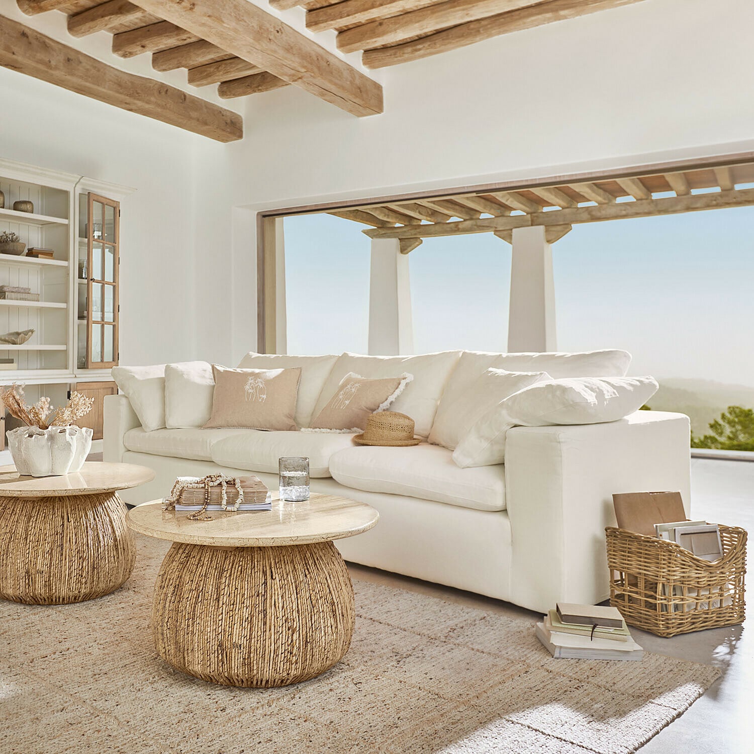 Sofá Everholt Sala acogedora con sofá blanco y dos mesas redondas de madera y ratán en tonos naturales
