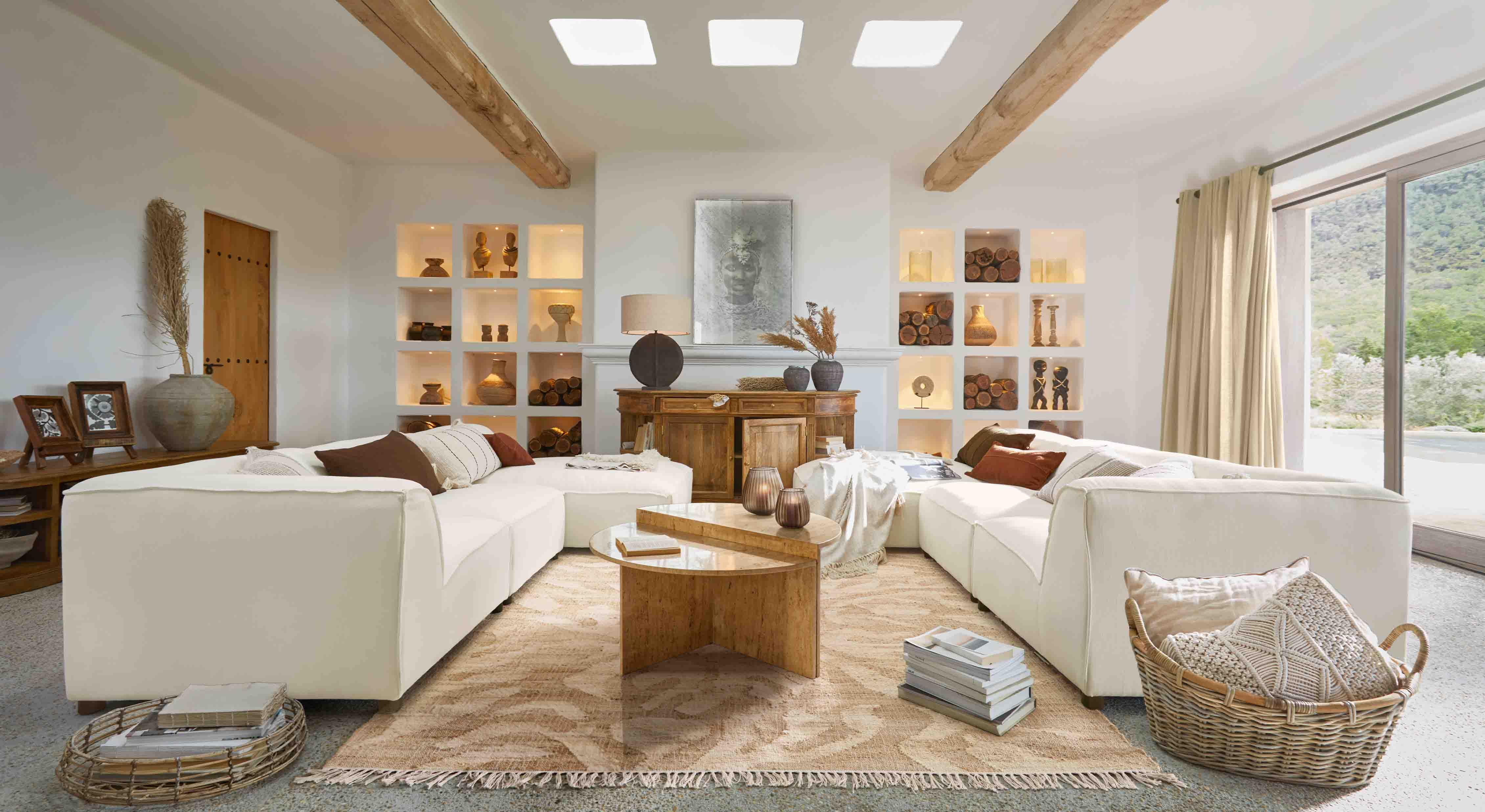 Salón amplio con sofá esquinero blanco, mesa de madera y decoración en tonos naturales cálidos