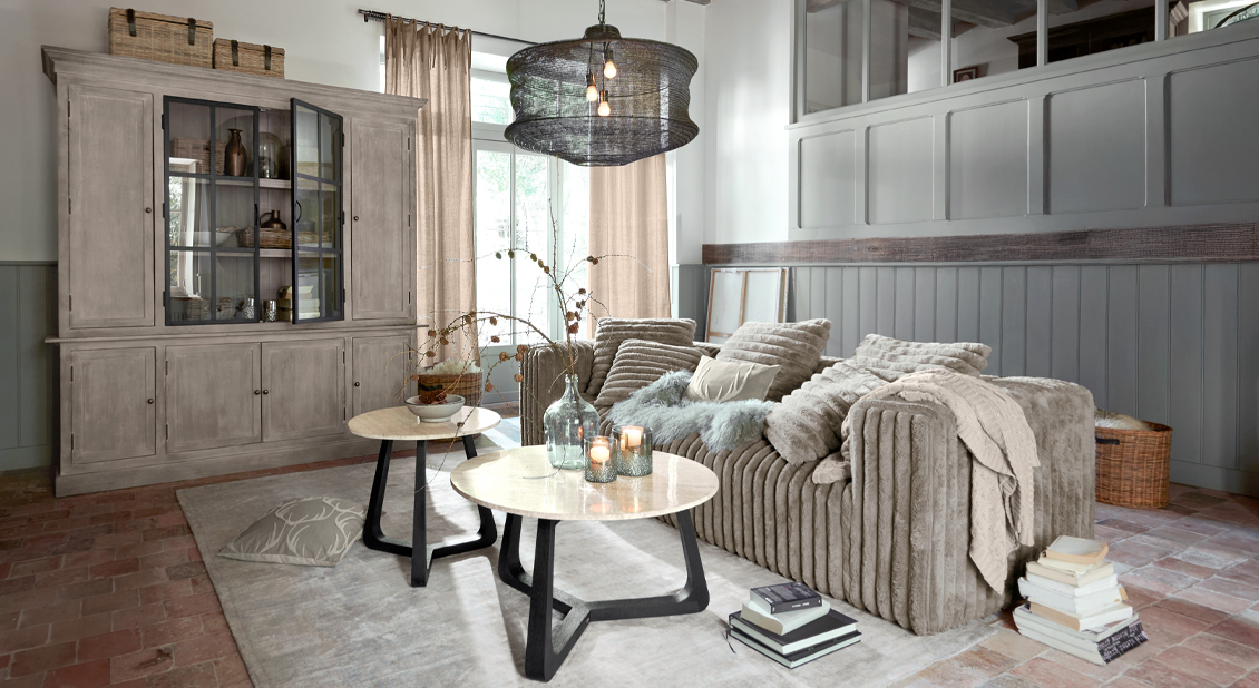 Sofá beige de tela suave en salón elegante con dos mesas de centro redondas de madera y metal