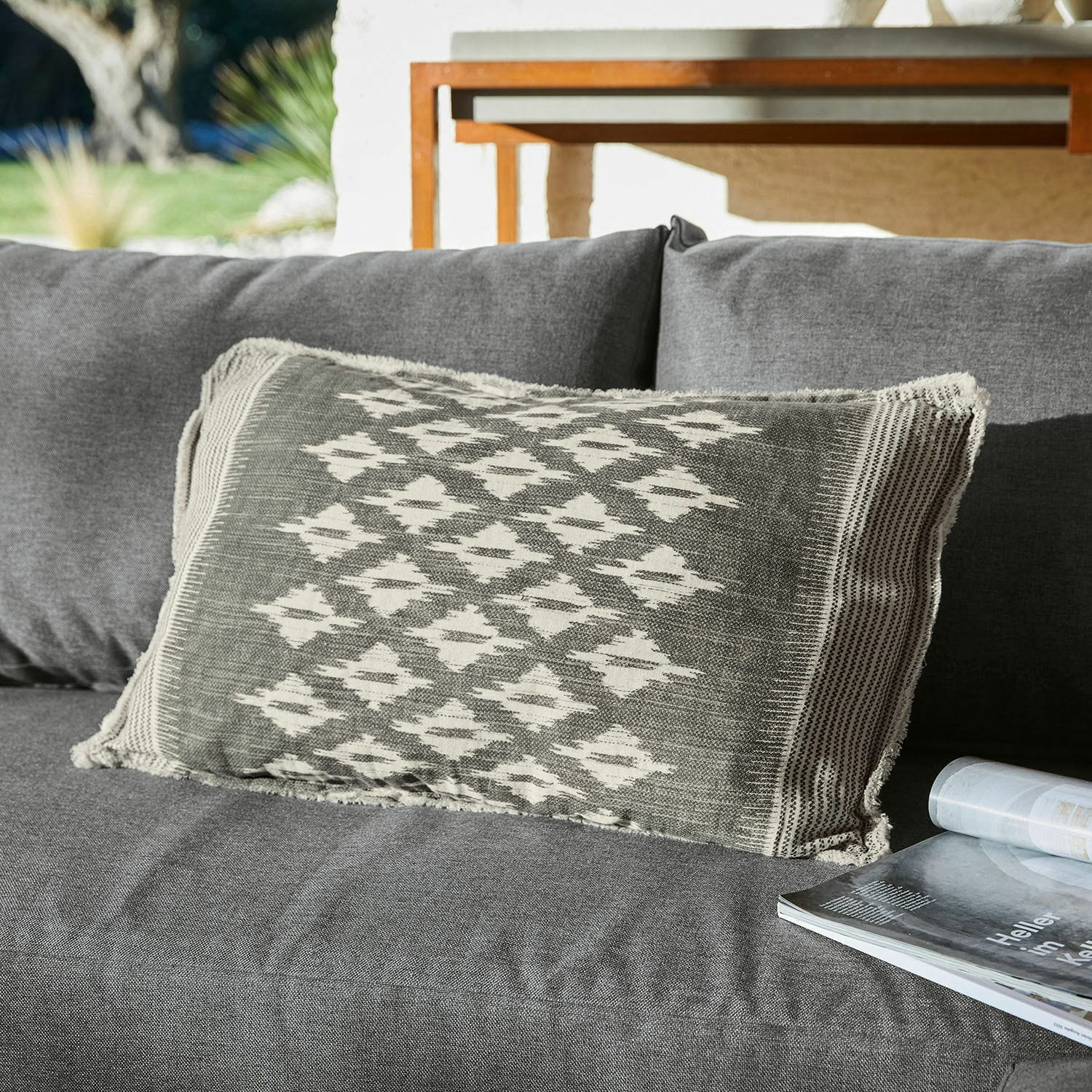 Cojín decorativo gris con patrón geométrico sobre sofá gris, textil para sala