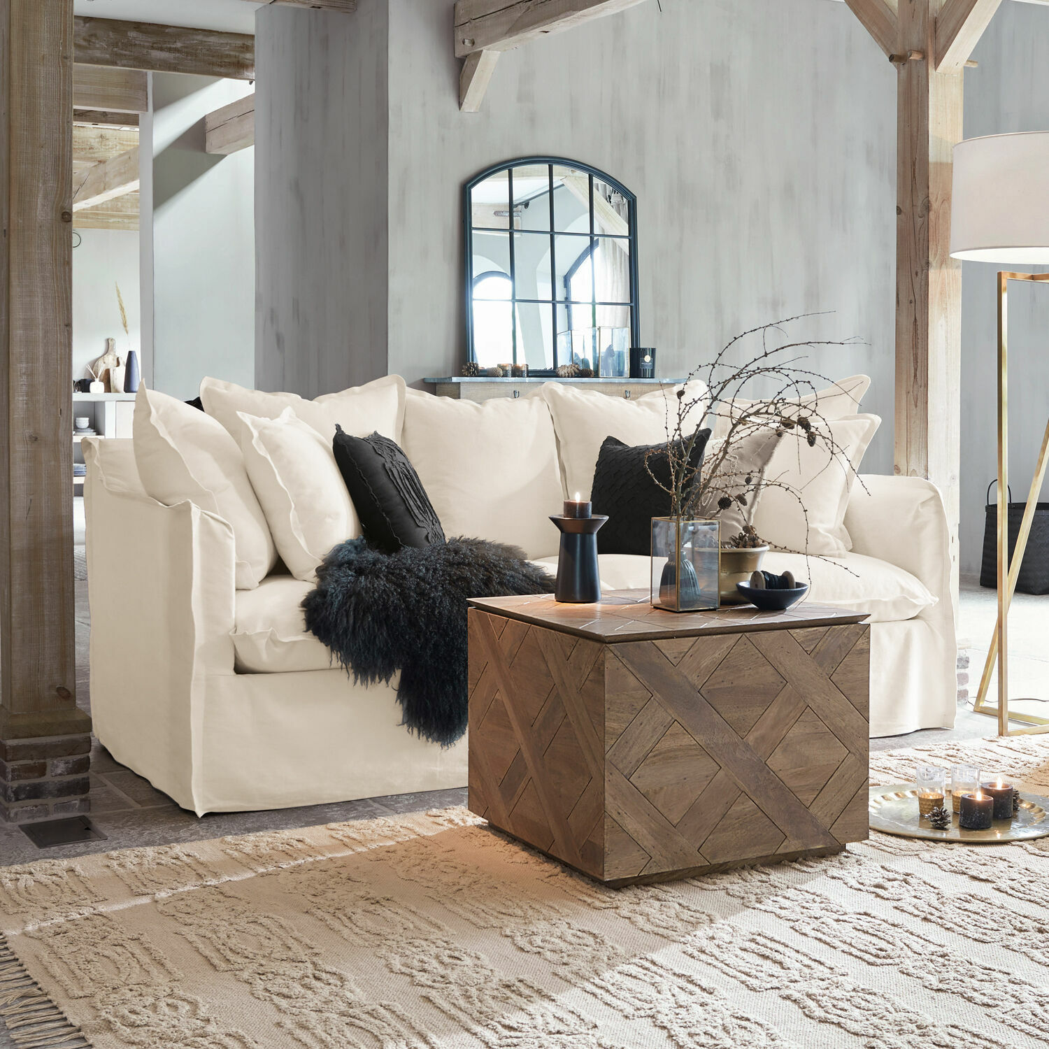 Sofá beige de tela con cojines negros y mesa de centro de madera en sala de estar luminosa