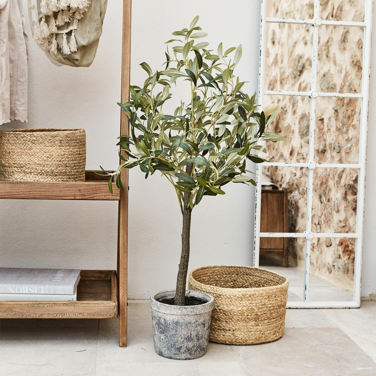 Planta decorativa Mariuccia Árbol de olivo artificial en maceta gris junto a cesta de mimbre y espejo con marco blanco