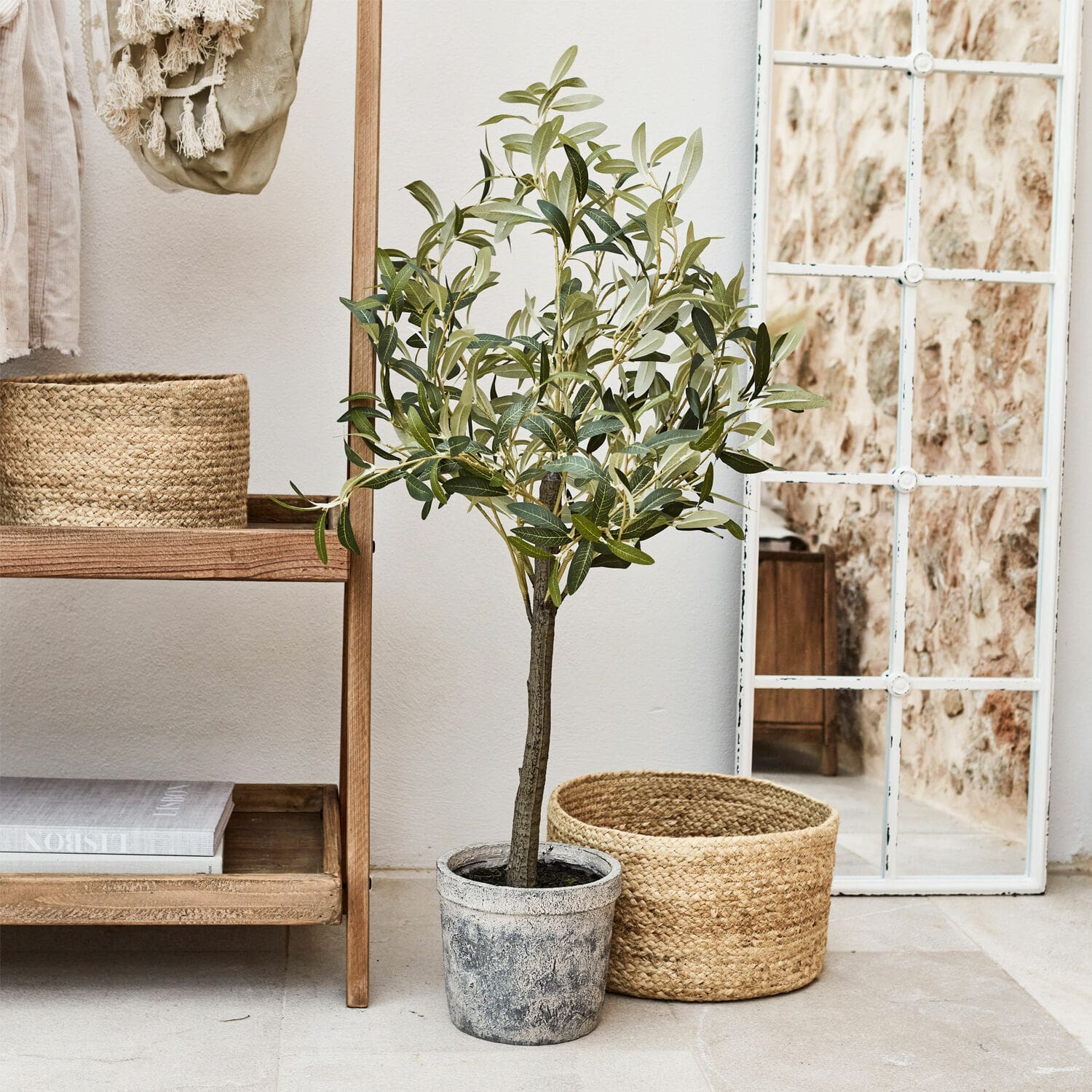 Planta decorativa Mariuccia Árbol de olivo artificial en maceta gris junto a cesta de mimbre y espejo con marco blanco
