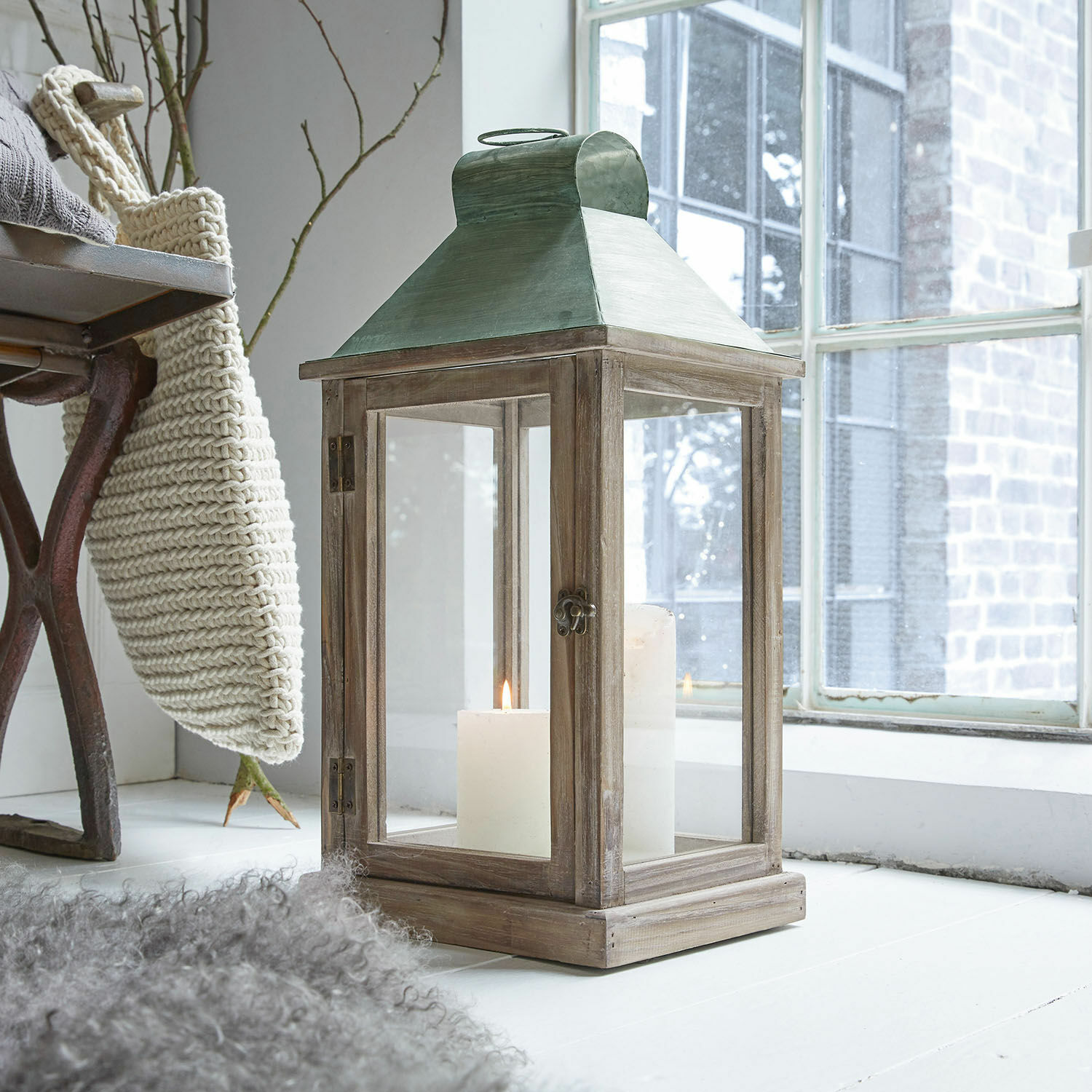 Linterna de madera con techo metálico verde y velas blancas, decoración para interiores