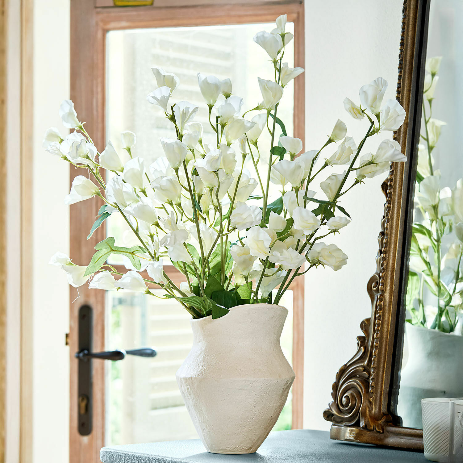 Juego de 6 flores Clavigny Jarrón de cerámica blanca con flores blancas decorativas sobre mesa junto a espejo antiguo