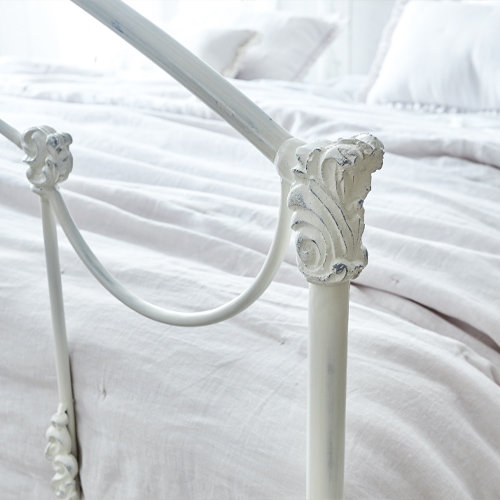 Cabecero de cama metálico blanco Canefield con detalles decorativos y ropa de cama clara
