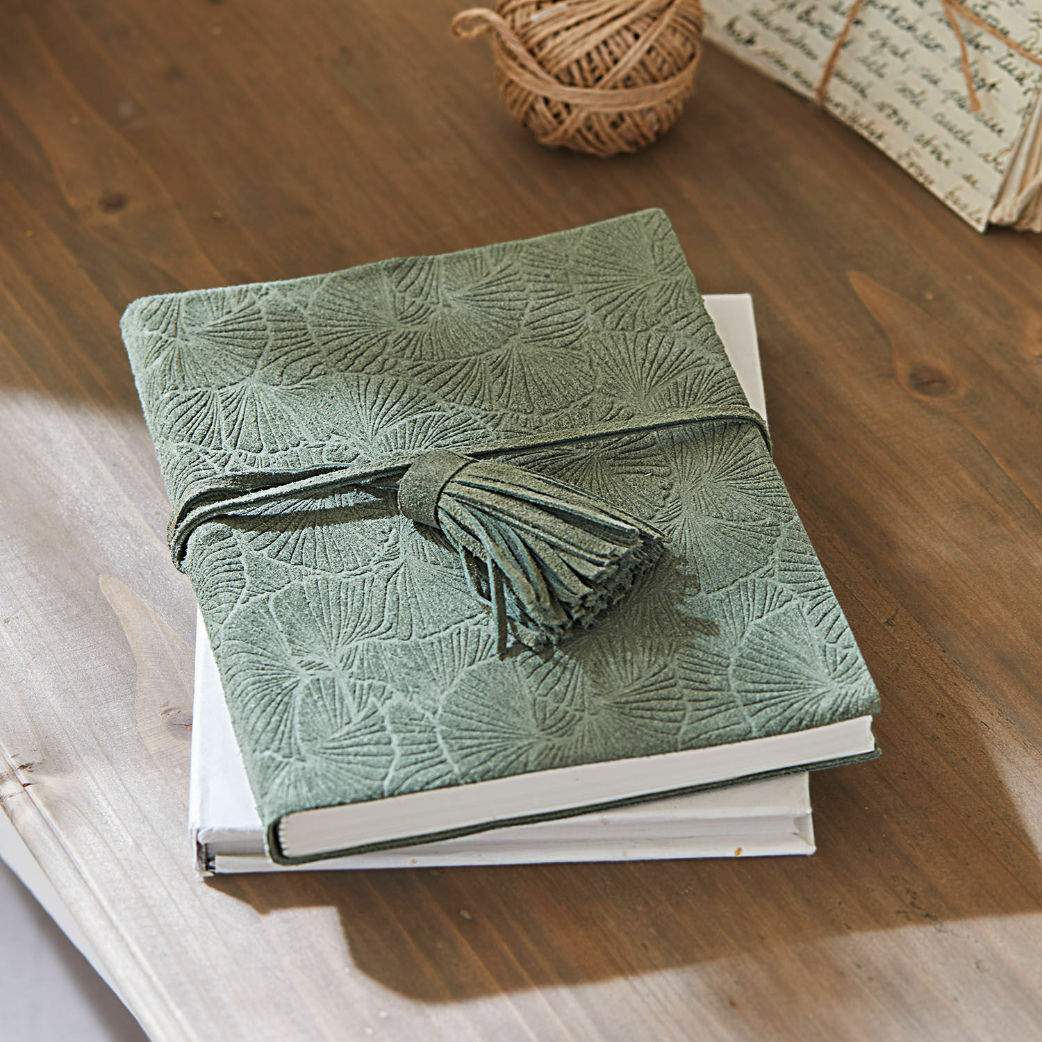 Cuaderno Brocton Cuaderno verde de ante con diseño en relieve y borla sobre mesa de madera, accesorios de escritura