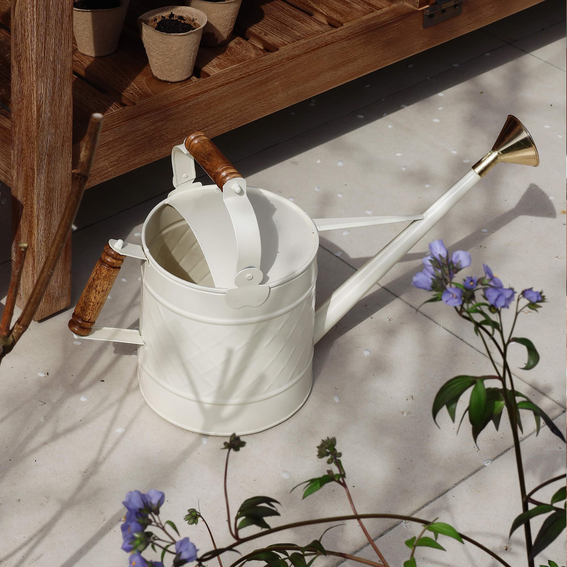 Regadera metálica blanca con asas de madera y pico de latón para jardinería