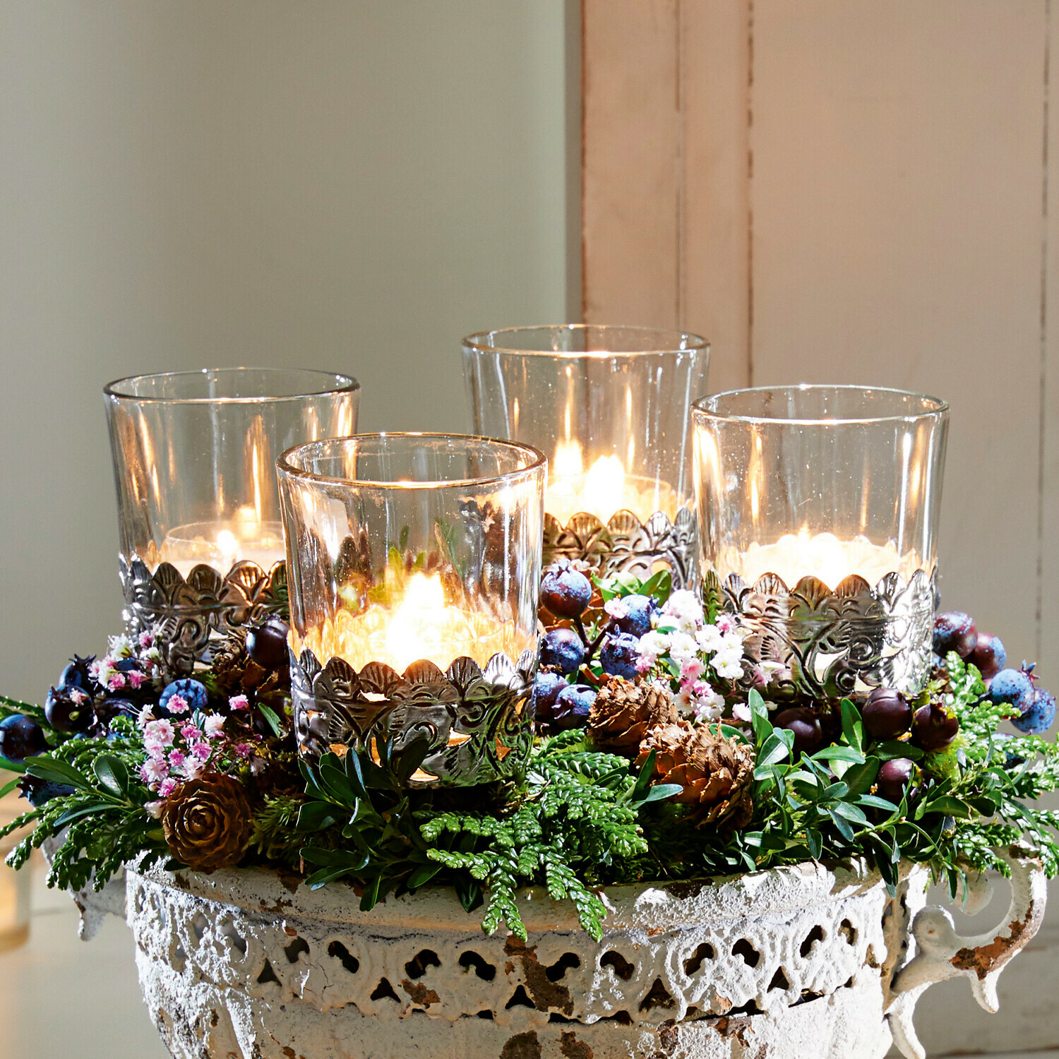 Set de 4 farolillos Pinelle Cuenco decorativo de metal envejecido con cuatro velas y adornos verdes sobre bandeja de madera