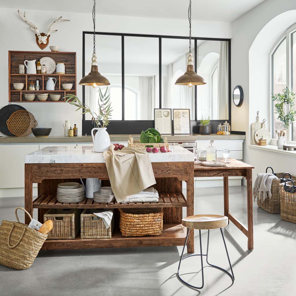 Cocina rústica con isla de madera y encimera de mármol, cestas naturales y decoración