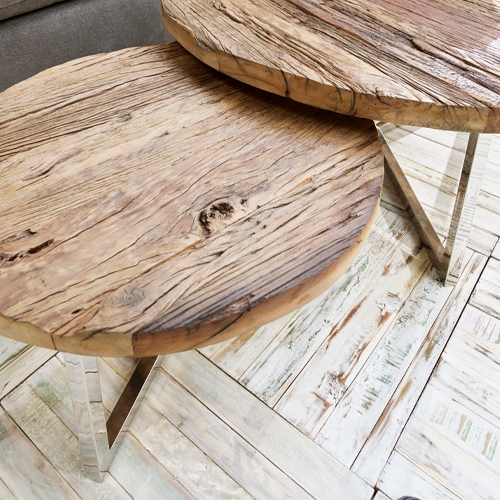 Dos mesas redondas de madera natural con patas metálicas sobre suelo claro, muebles modernos