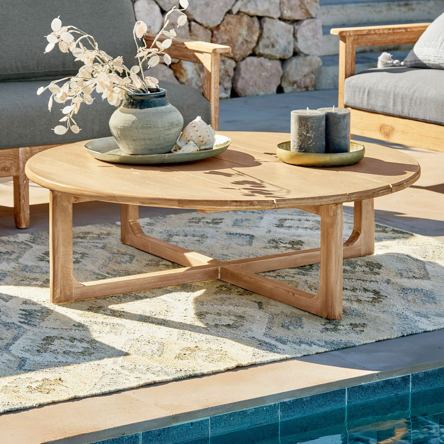 Mesa de centro Tewksbury Mesa de centro redonda de madera de teca natural en terraza junto a piscina con decoraciones