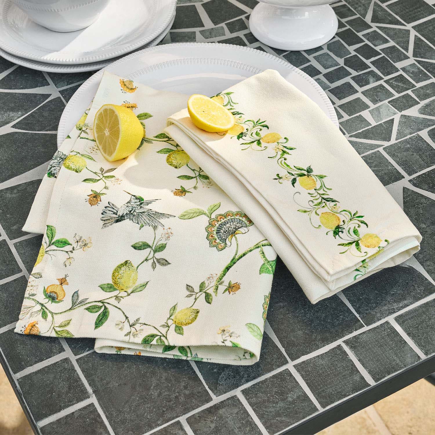 Servilletas de lino con diseño de limones y pájaros sobre mesa de piedra gris, decoración de mesa
