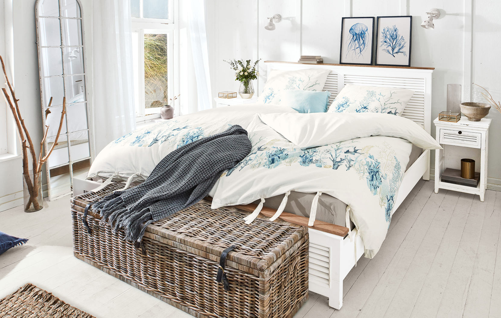 Dormitorio estilo marítimo con cama blanca y ropa de cama con motivos marinos azules y corales