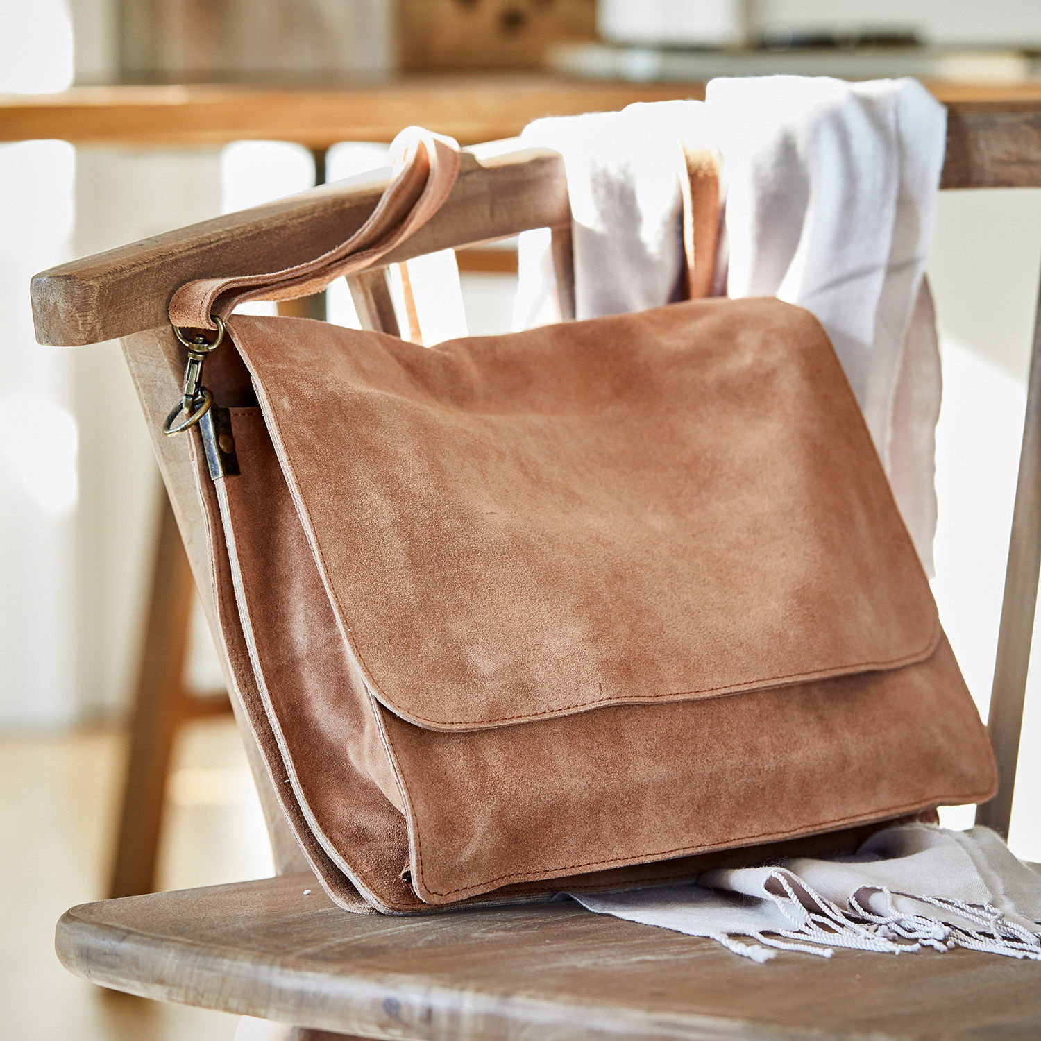 Bolso Chanzelle Bolso marrón de ante suave sobre una silla de madera, accesorio de moda para uso diario