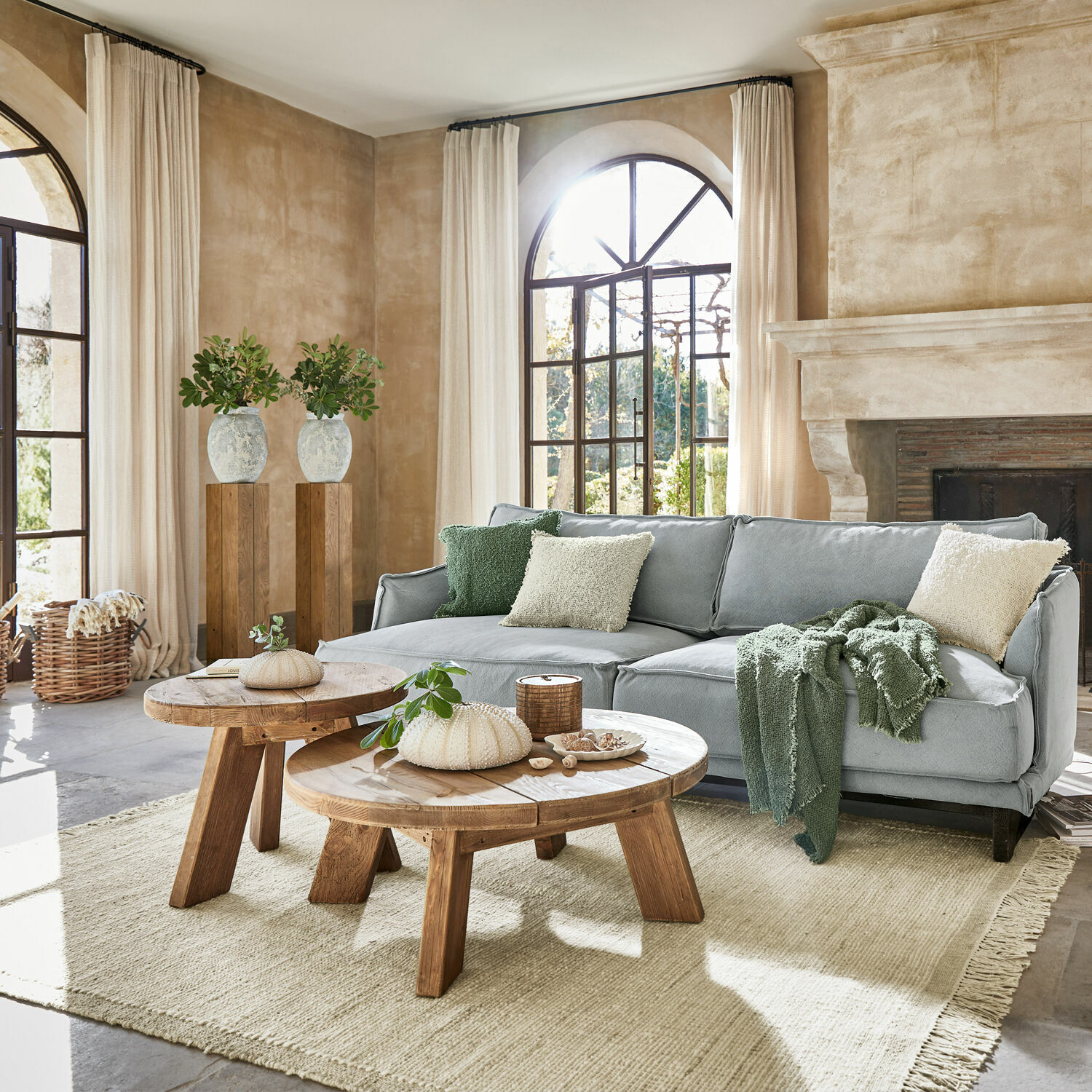 Sala acogedora con sofá gris, mesas de centro de madera y alfombra natural en tonos claros
