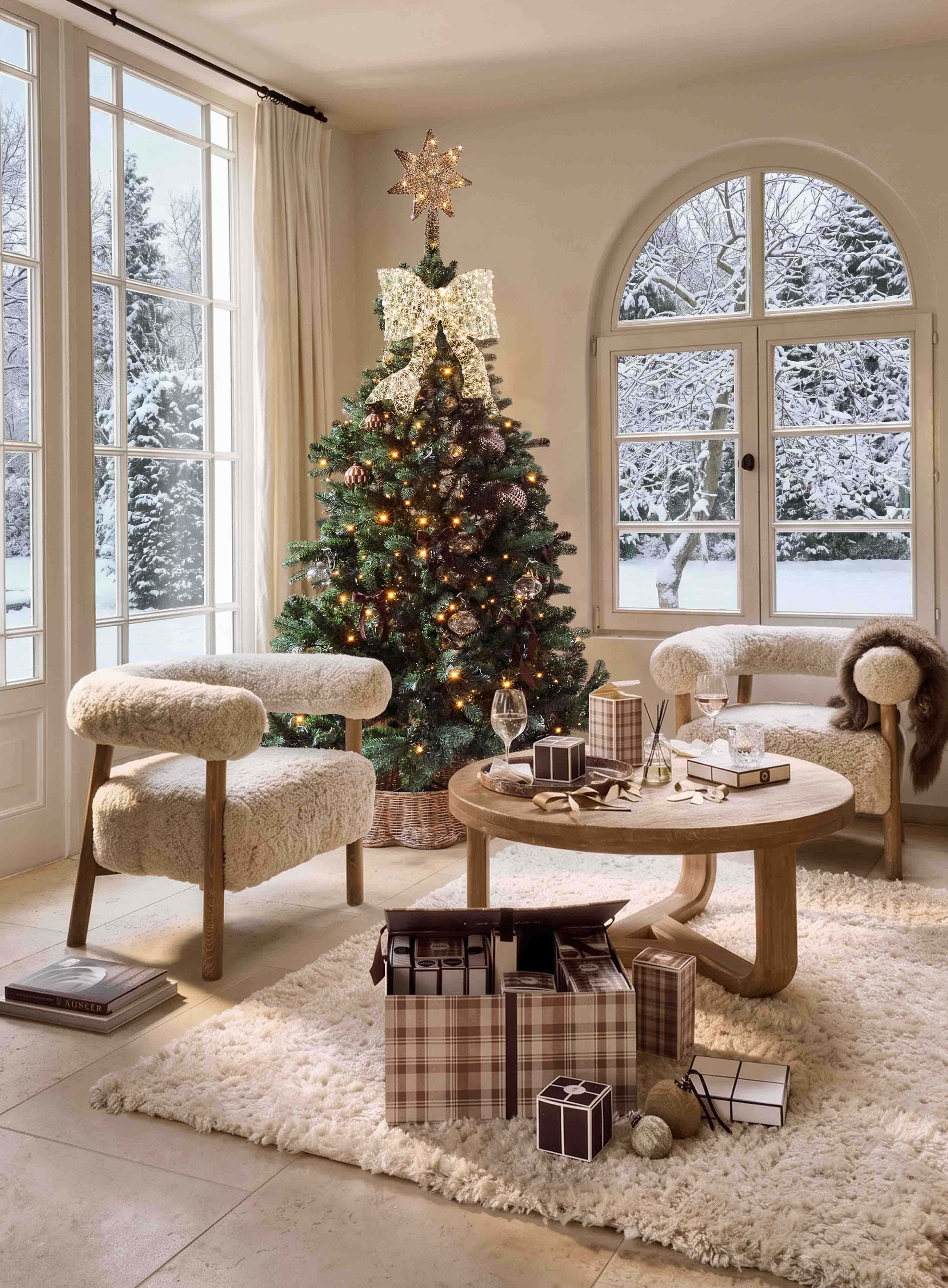 Árbol de Navidad decorado con estrella luminosa y gran lazo en salón acogedor con vista a jardín nevado