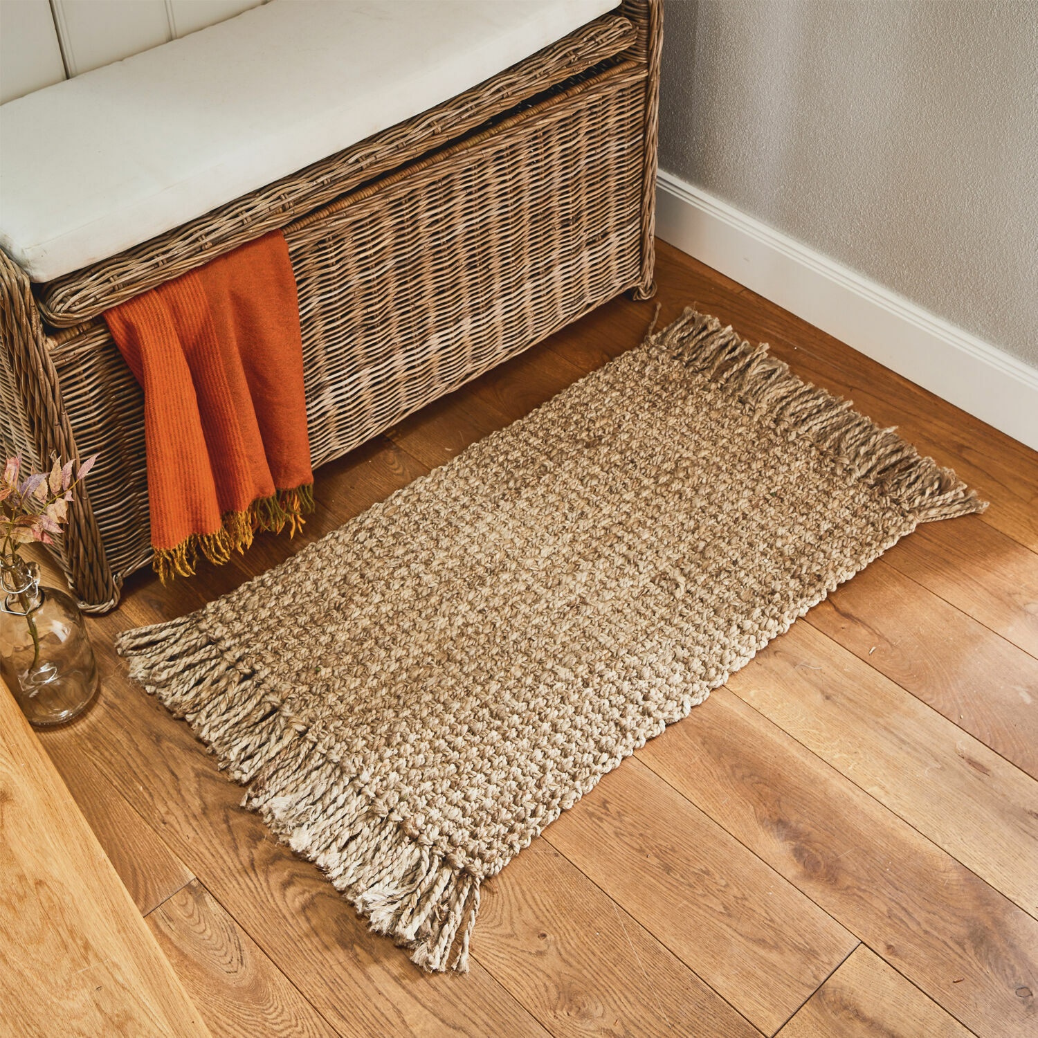 Felpudo Moody Alfombra beige con flecos de material natural sobre suelo de madera en interior acogedor