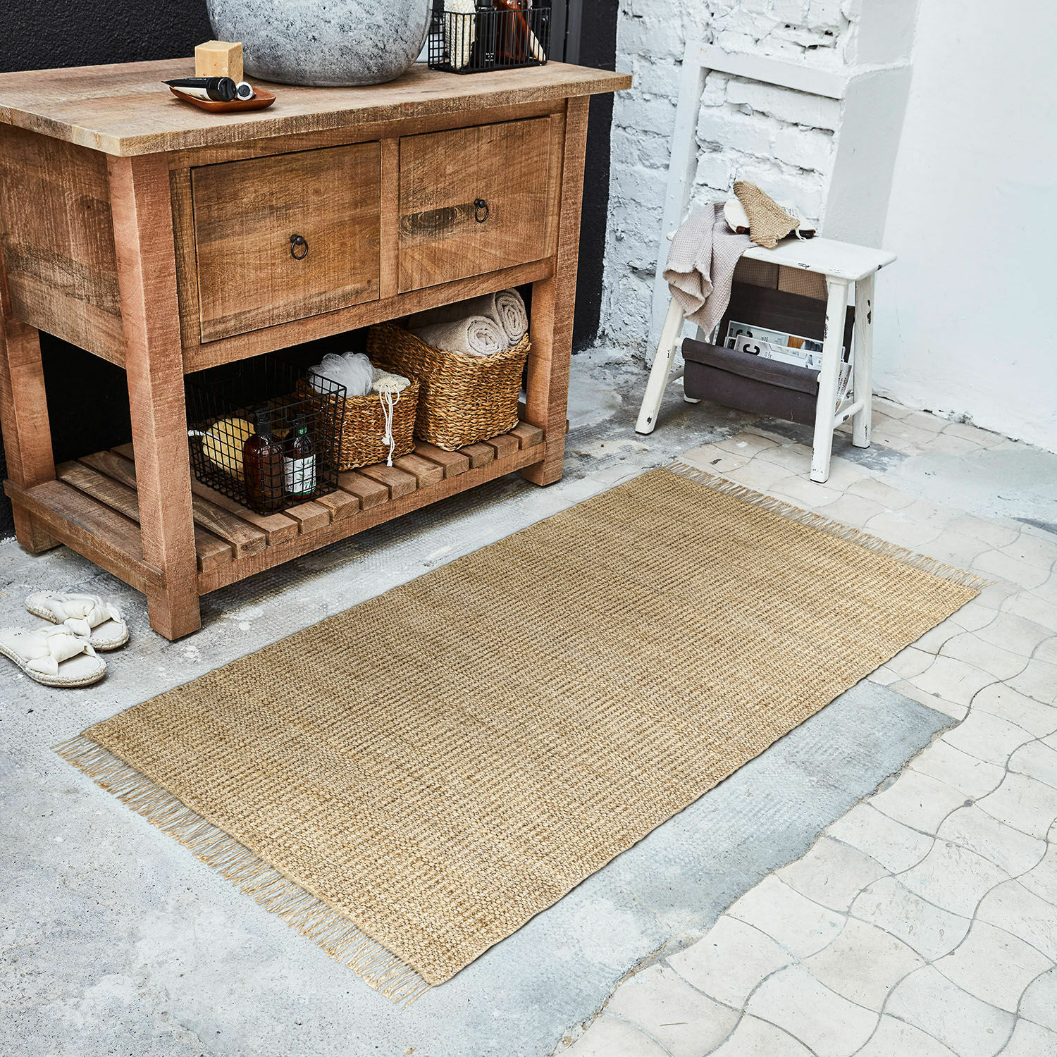 Alfombra Hermitage Alfombra natural de yute beige en el suelo junto a una cómoda de madera y un taburete blanco
