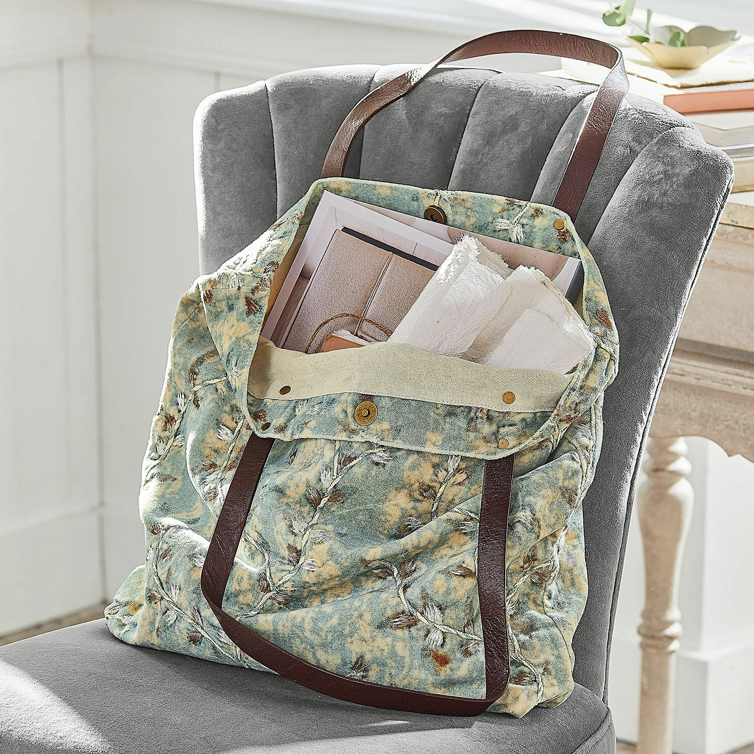 Bolso LaRoux Bolsa de tela suave con patrón verde y beige y asas marrones sobre silla gris