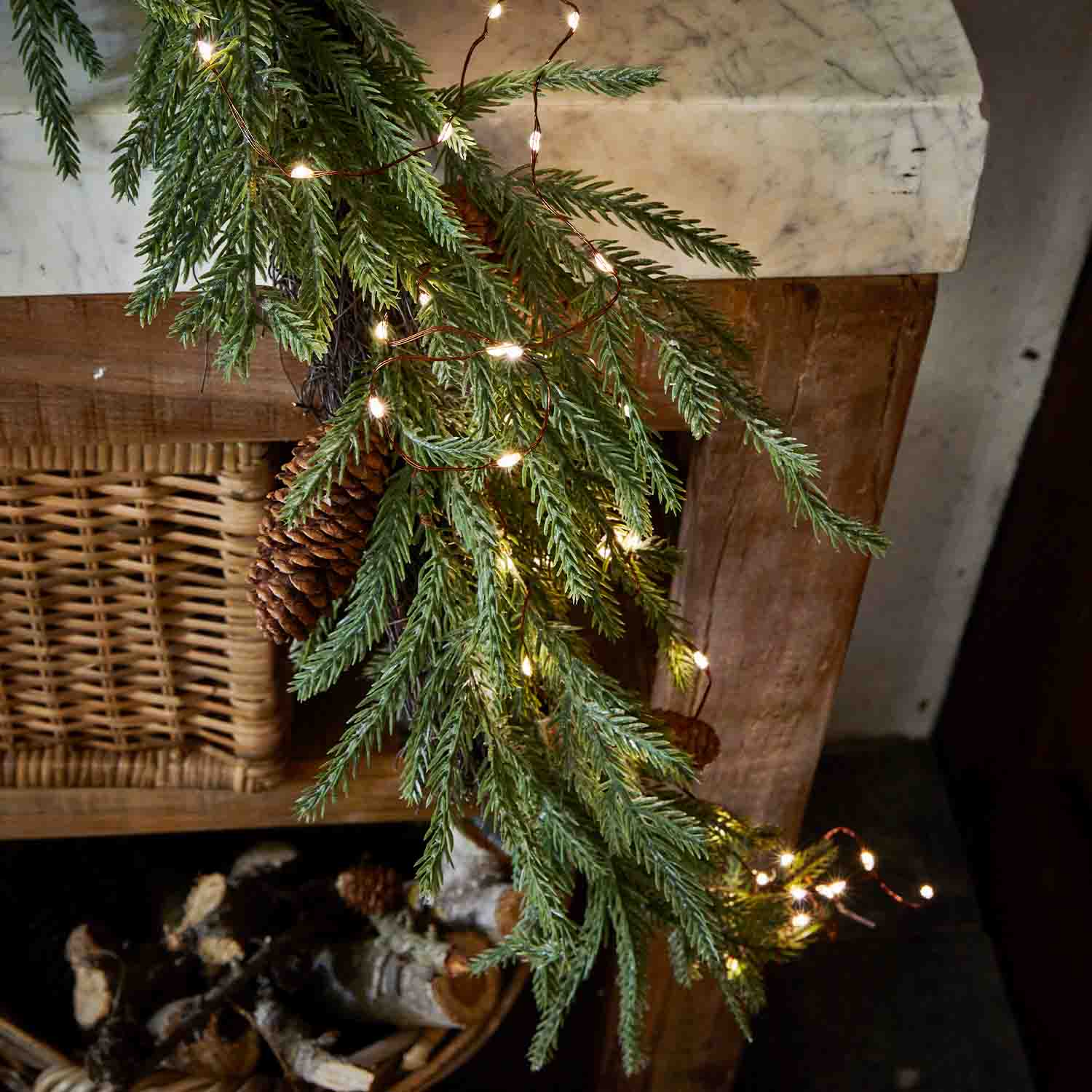 Rama de abeto con piña y luces LED en chimenea de madera, decoración navideña